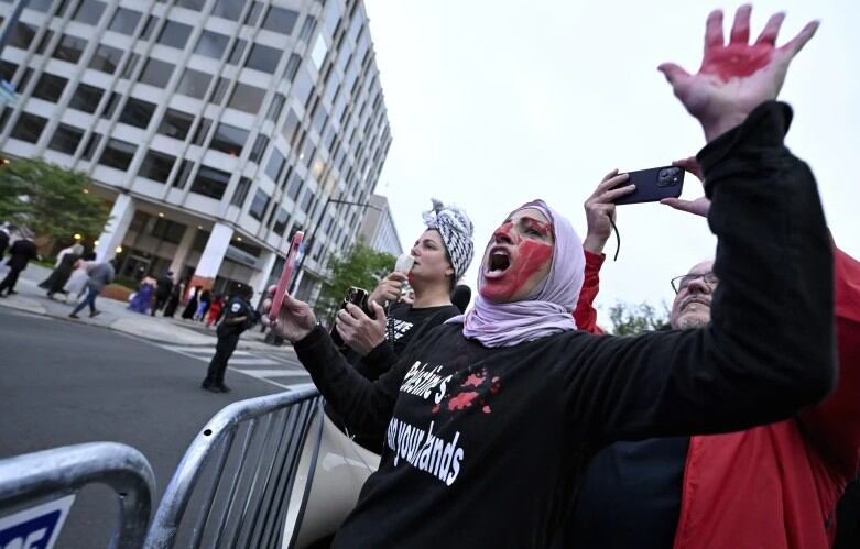 Un manifestante con pintura roja en la mano y la cara es visto detrás de una barricada policial durante una protesta pro-palestina por la guerra entre Israel y Hamas en la cena de la Asociación de Corresponsales de la Casa Blanca, el sábado 27 de abril de 2024, en Washington.
