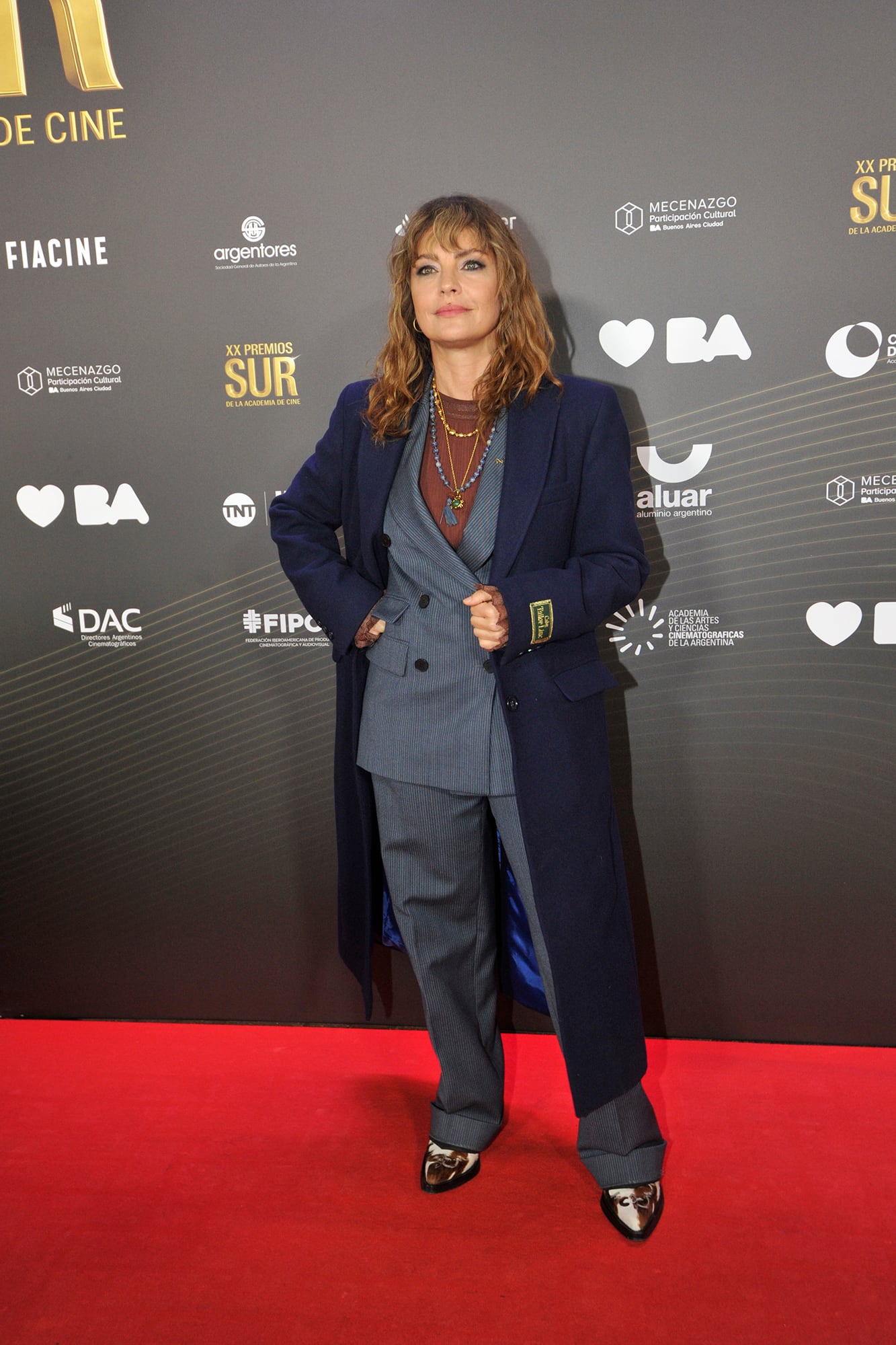 Otra figura que eligió la gama de los azules para esta noche fue Dolores Fonzi. La actriz y directora, que lideró las nominaciones con su película Belén, apostó por un conjunto a rayas, un tapado de paño y botas texanas