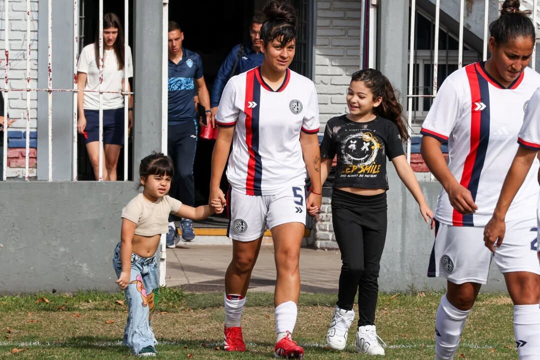Con la camiseta de San Lorenzo, su actual club, ingresa con su hija Alaia (derecha) de la mano