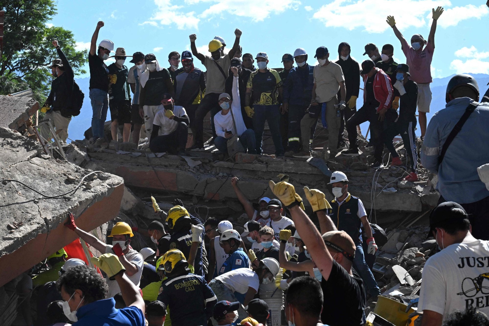 Personas y rescatistas buscan sobrevivientes entre los escombros de un edificio derrumbado tras un terremoto en Cali, Colombia
