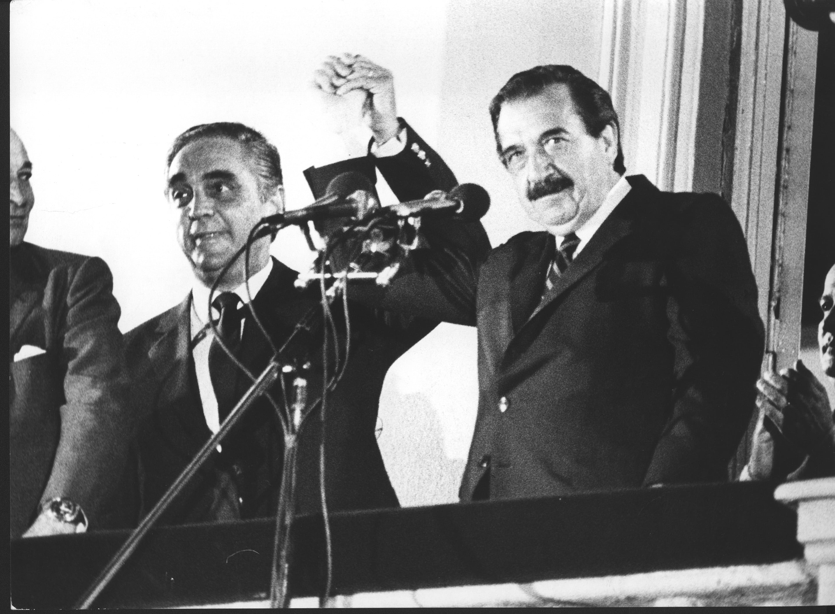 Raúl Alfonsín con el brazo alto junto a su compañero de formula Víctor Martínez