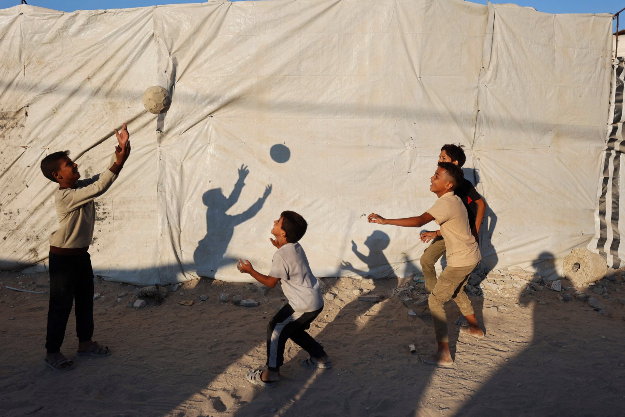 Niños palestinos desplazados juegan con una pelota frente a una tienda de campaña en Gaza, el 31 de agosto de 2026. (Foto de Omar AL-QATTAA / AFP)