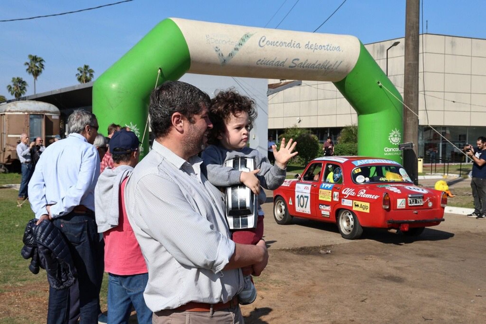 Las familias no solamente compiten: este padre le contagia a su hijo la afición al automovilismo, entre los coches históricos de verdad y un auto de juguete, en la largada de la última etapa, en Concordia.