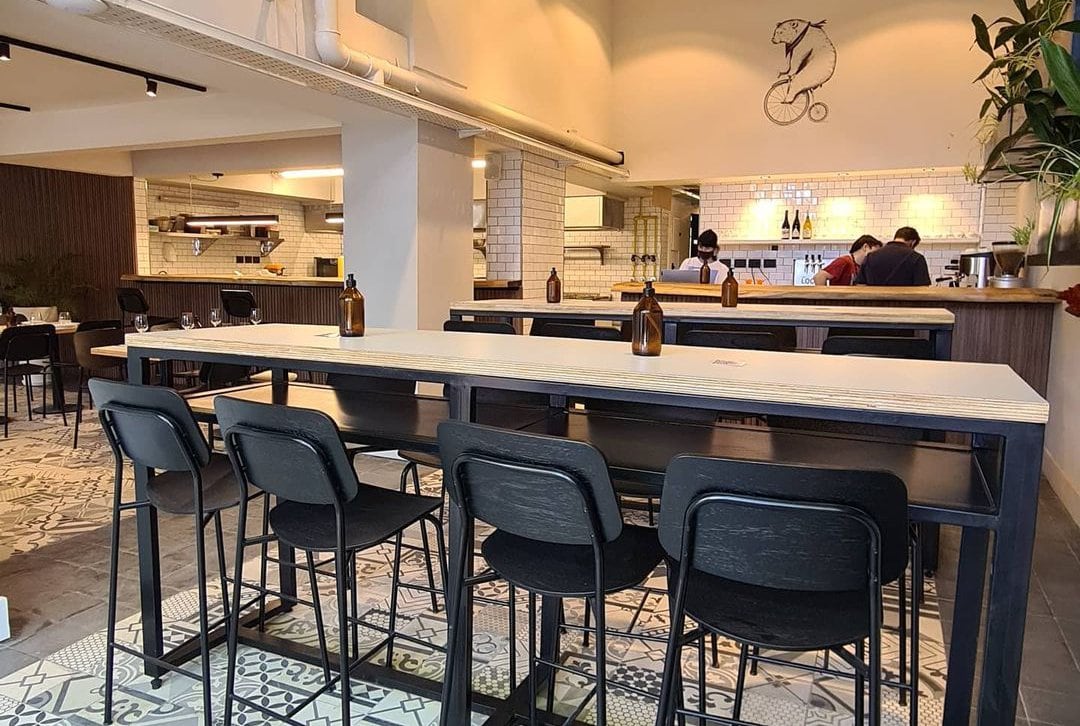 El discreto salón con la cocina integrada mediante una barra de despacho marca el ritmo del servicio en un ambiente relajado