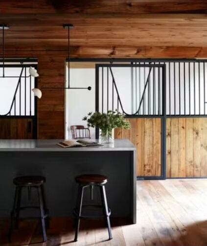 La isla de la cocina está enmarcada en hormigón y puertas correderas reutilizadas de los establos originales para caballos