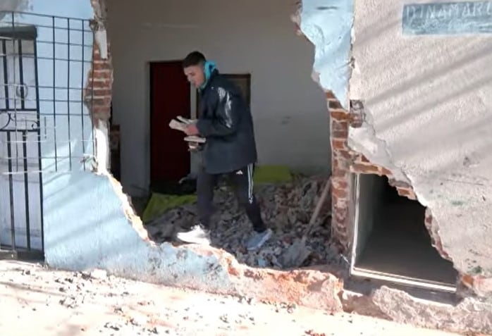 Un joven saca sus pertenencias de lo que quedó de la habitación