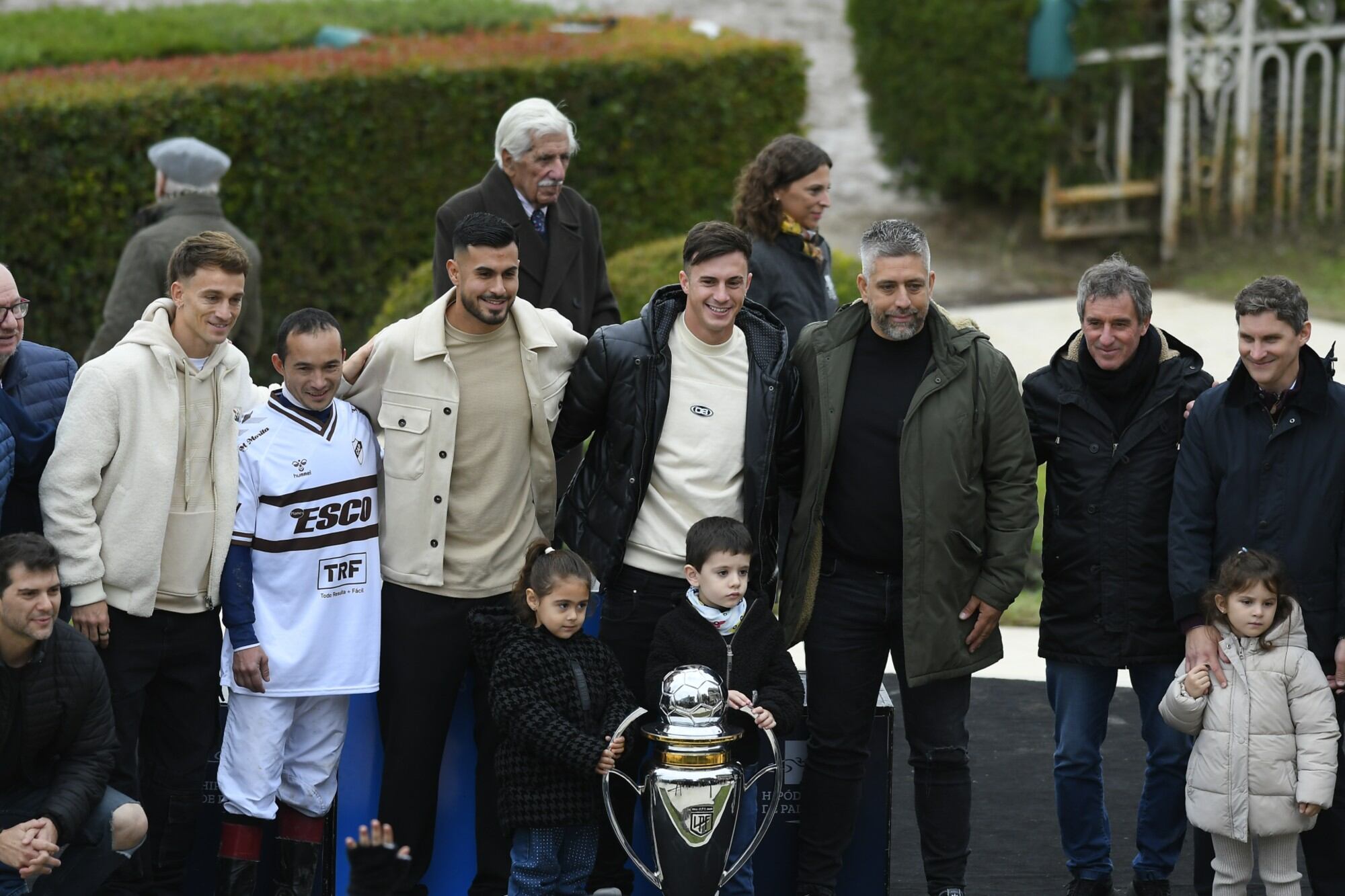 Augusto Lotti, Ignacio Vázquez, Guido Mainero, jugadores de Platense, y el presidente Sebastián Ordoñez, junto al jockey Ortega Pavón (con la camiseta) y parte del equipo del stud ganador