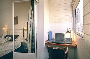 Un balcón cerrado se aprovecha como miniestudio con un escritorio hecho con una tabla de madera amurada a lo ancho del espacio