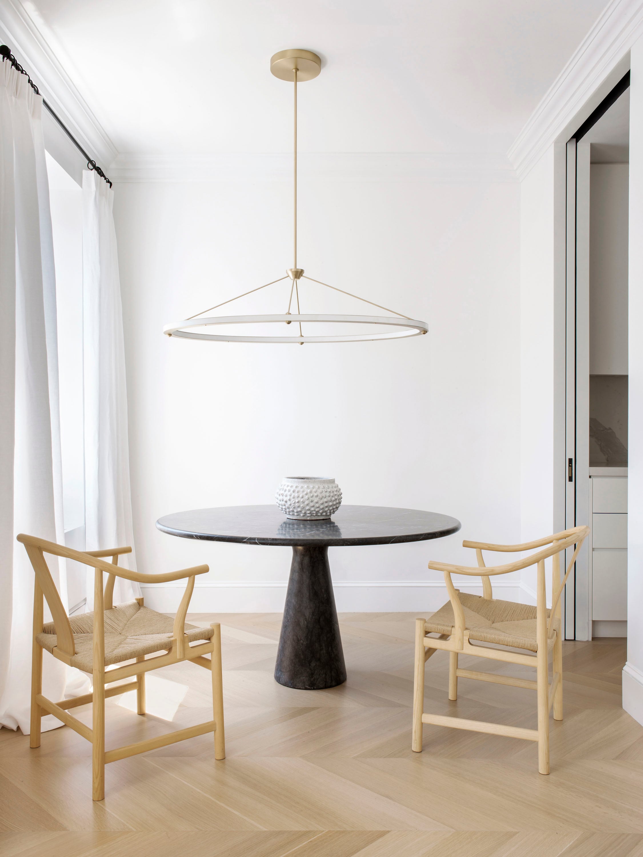 Mesa de comedor de mármol firmada por Angelo Mangiarotti. Sillas ‘China’ de Hans J. Wegner (todo Suite NY), lámpara ‘Halo’ de Paul Loebach para Roll & Hill.