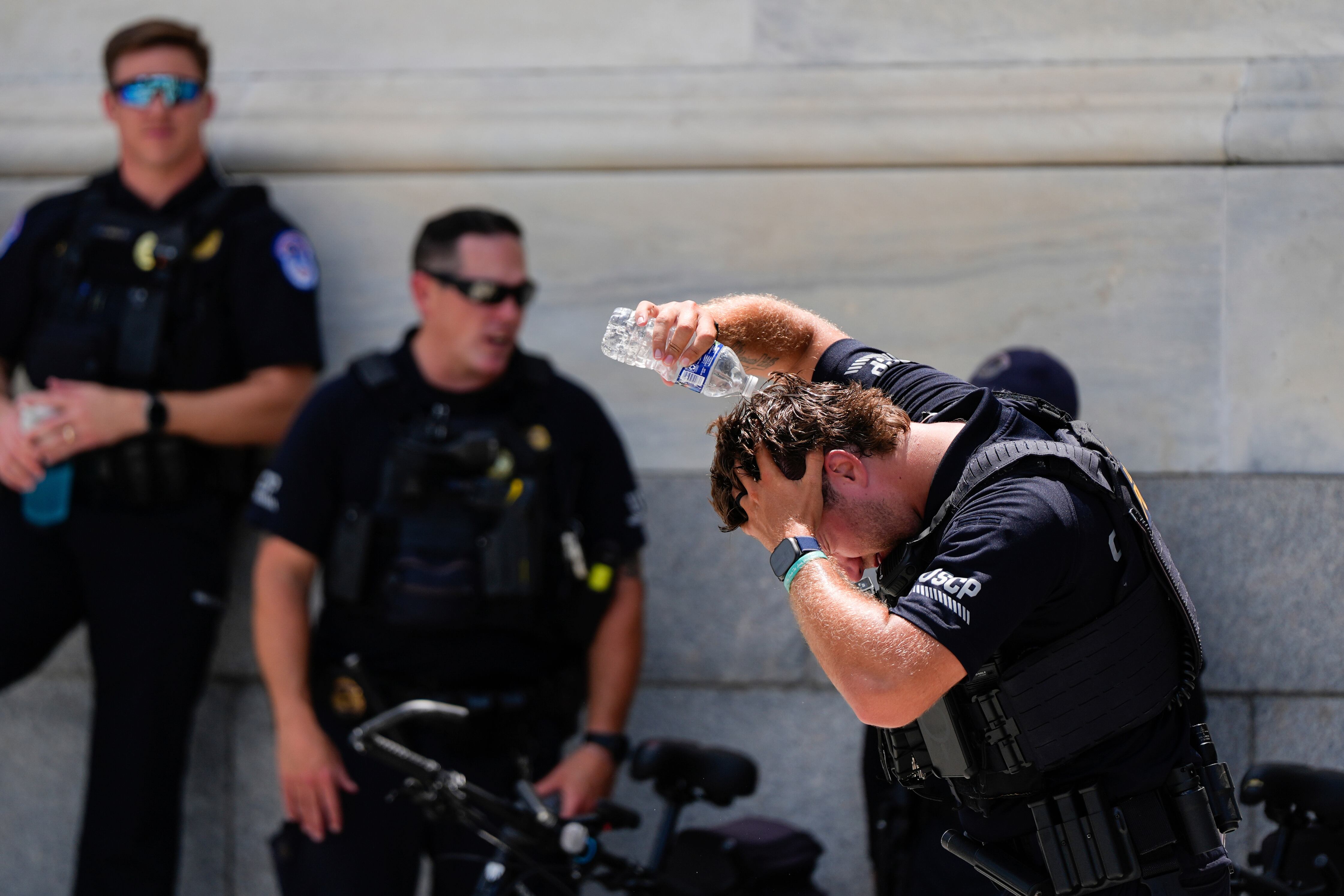 Un policía del Capitolio de Estados Unidos vierte agua en su cabeza, el miércoles 25 de junio de 2025 fuera del Capitolio, en Washington. (AP Foto/Julia Demaree Nikhinson)
