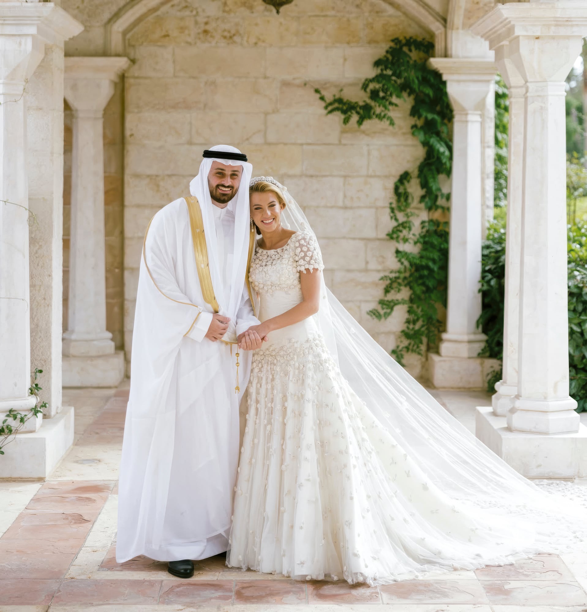 La princesa Sara y Ali Al Sawwaf en su primera foto como marido y mujer. La novia lució un traje de corte clásico, con el cuerpo ajustado, escote redondeado y mangas cortas, confeccionado en tul y completamente cubierto con aplicaciones florales en relieve, igual que la falda, de volumen y gran caída, que terminaba en una larga cola. Remataba el look nupcial con un velo que se fundía con la silueta del vestido, discretos pendientes y un ramo de flores blancas