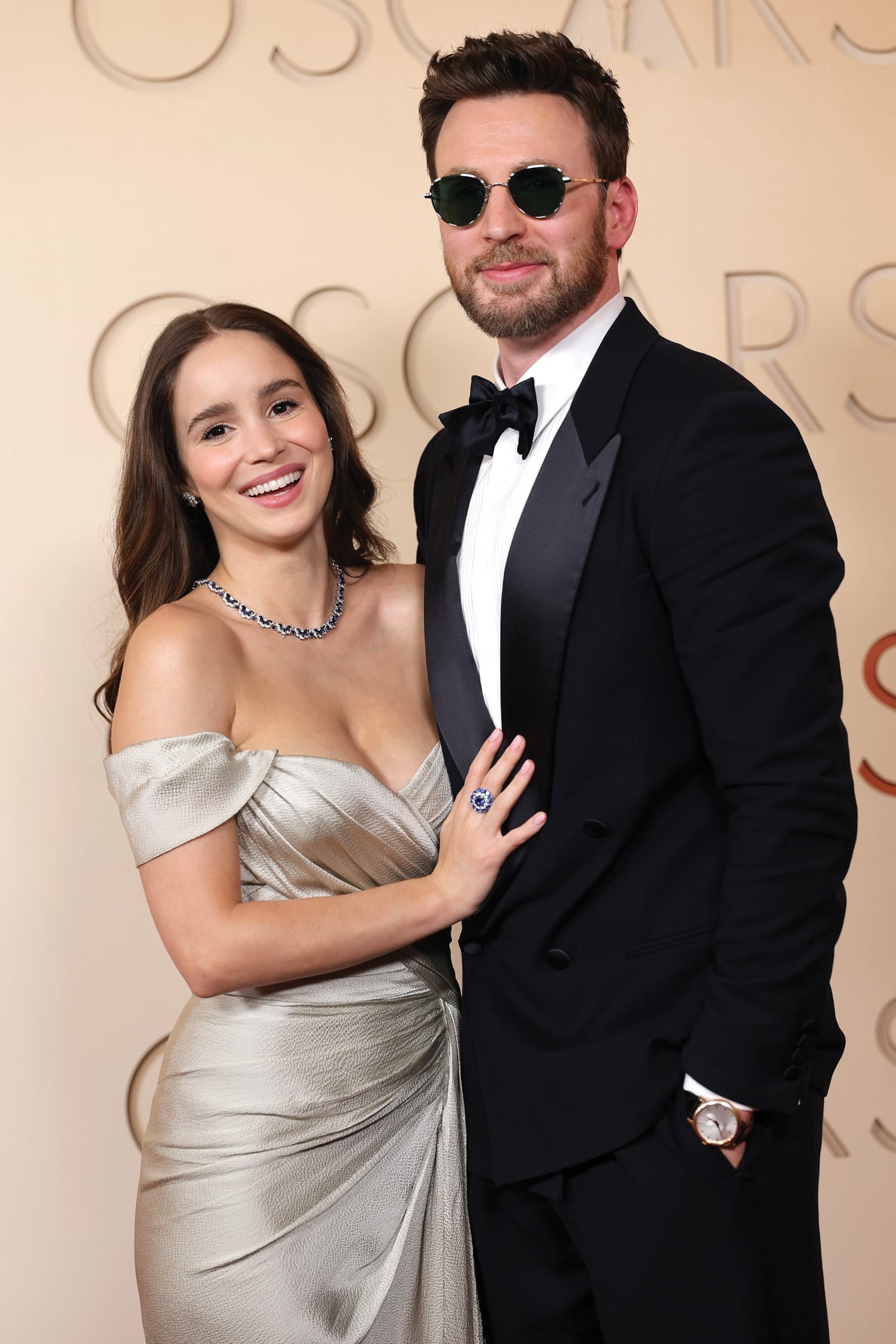 Chris Evans optó por un smoking clásico de Giorgio Armani con reloj Chopard mientras que su mujer, la bella actriz portuguesa Alba Baptista, eligió un modelo drapeado metalizado de Zuhair Murad