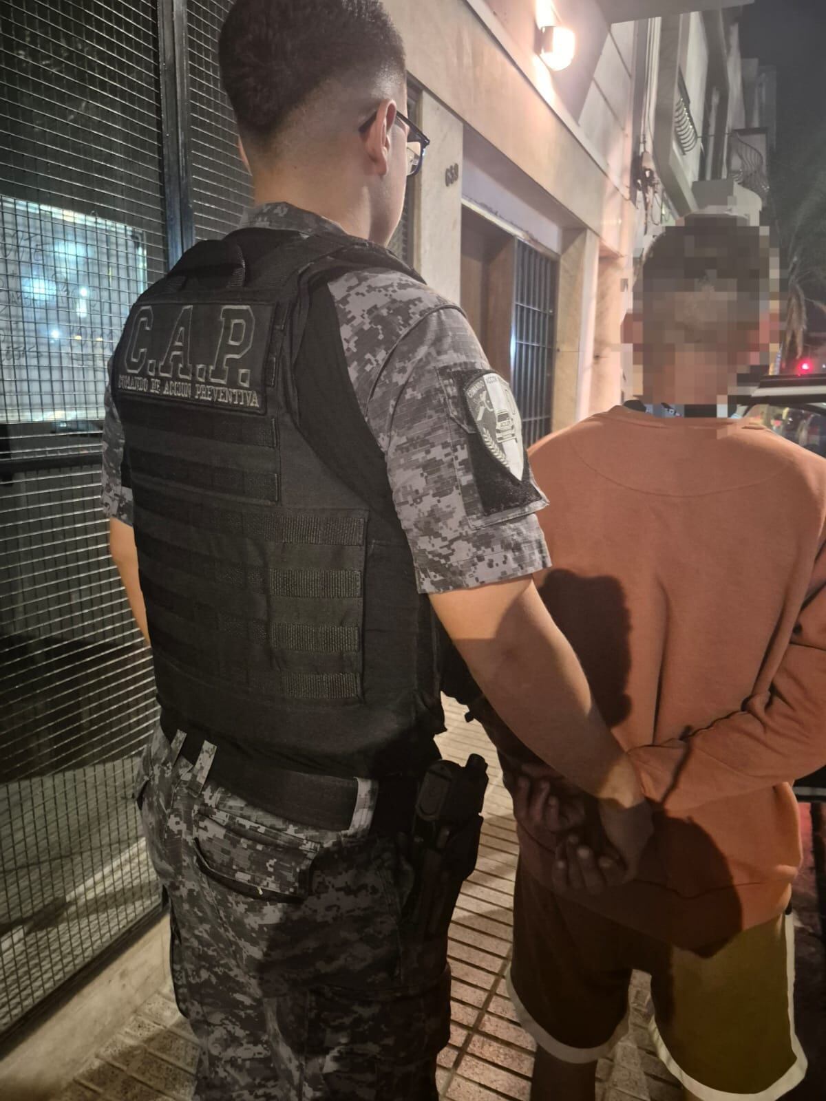 Un efectivo del Cuerpo de Acción Preventiva junto al sospechoso en la vereda del edificio de barrio Alberdi