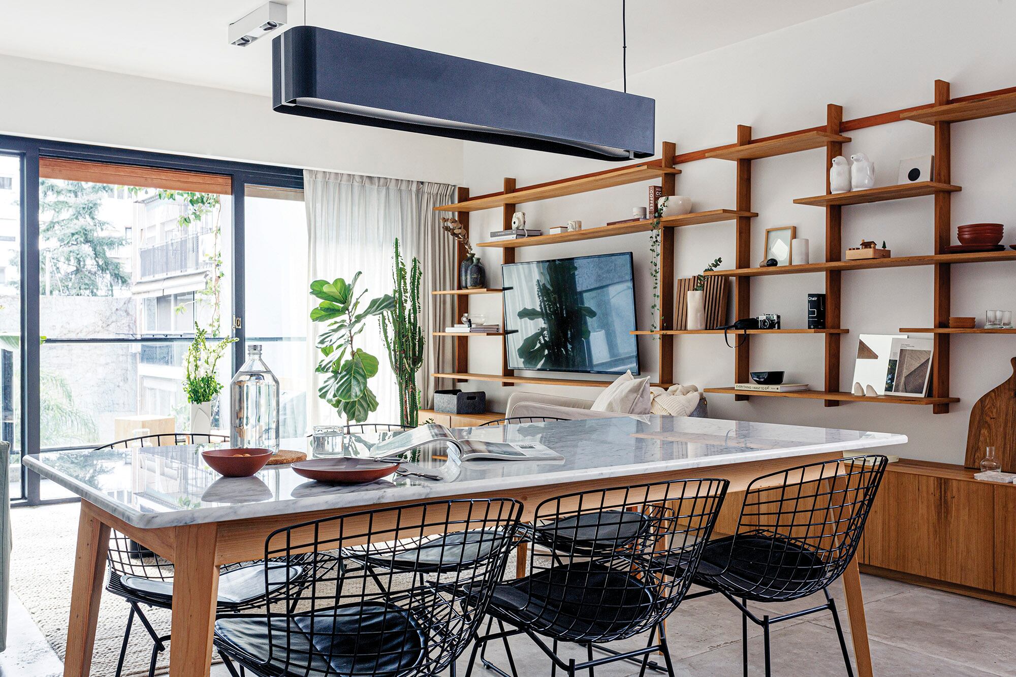 Mesa con tapa de mármol de Carrara y base de pino Brasil (Arq. Sofía Ledesma), sillas ‘Bertoia’, lámpara ‘Grisín’ (La Feliz).