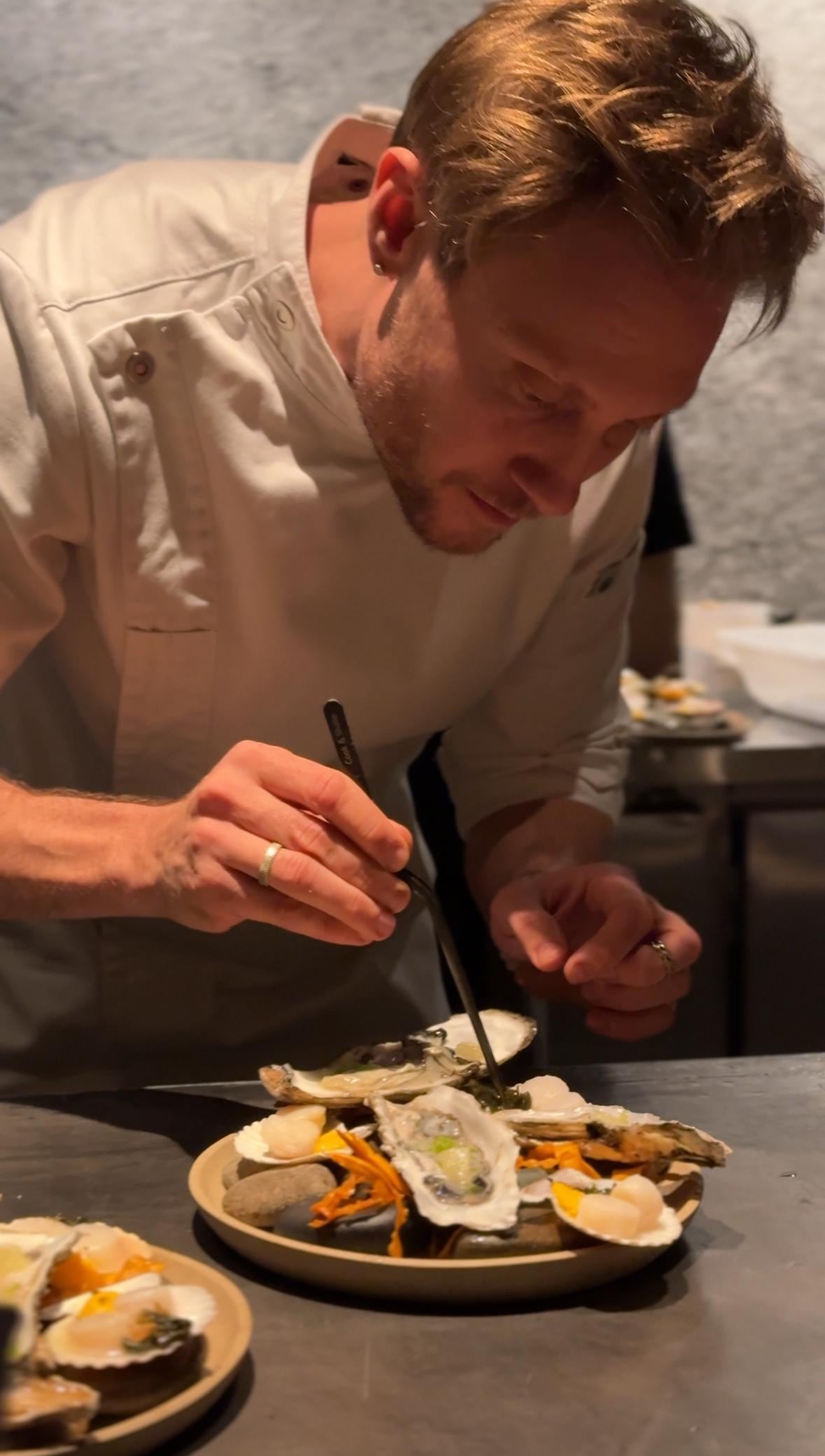 Kosta en la preparación de ostras y vieiras frescas con salsa de zanahoria, zucchini y jengibre