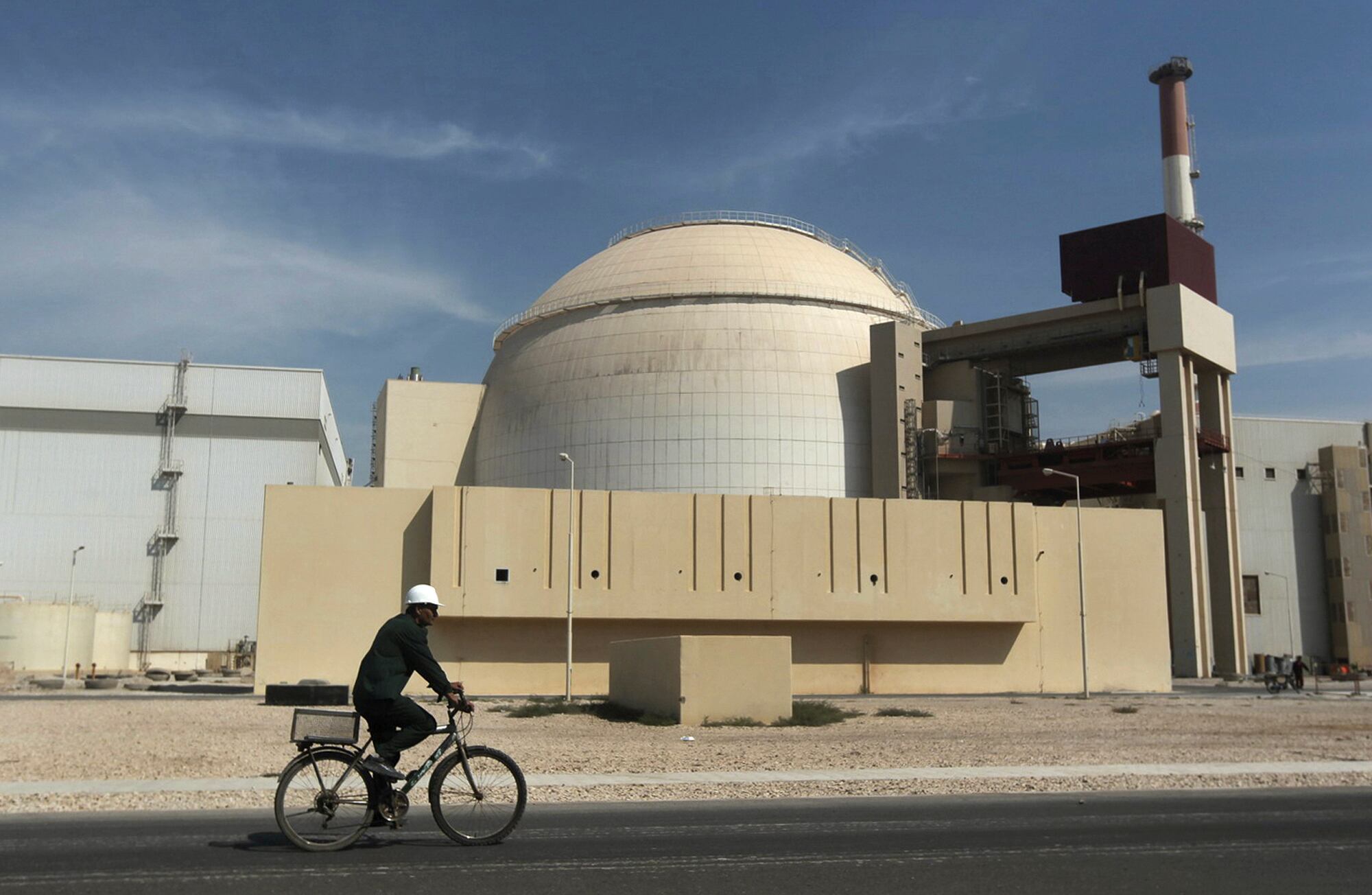 ARCHIVO-– Un trabajador conduce una bicicleta frente al reactor de la planta nuclear de las afueras de la ciudad de Bushehr, en el sur de Irán