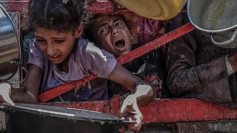 Niñas intentan obtener algo de comida en una cocina comunitaria.