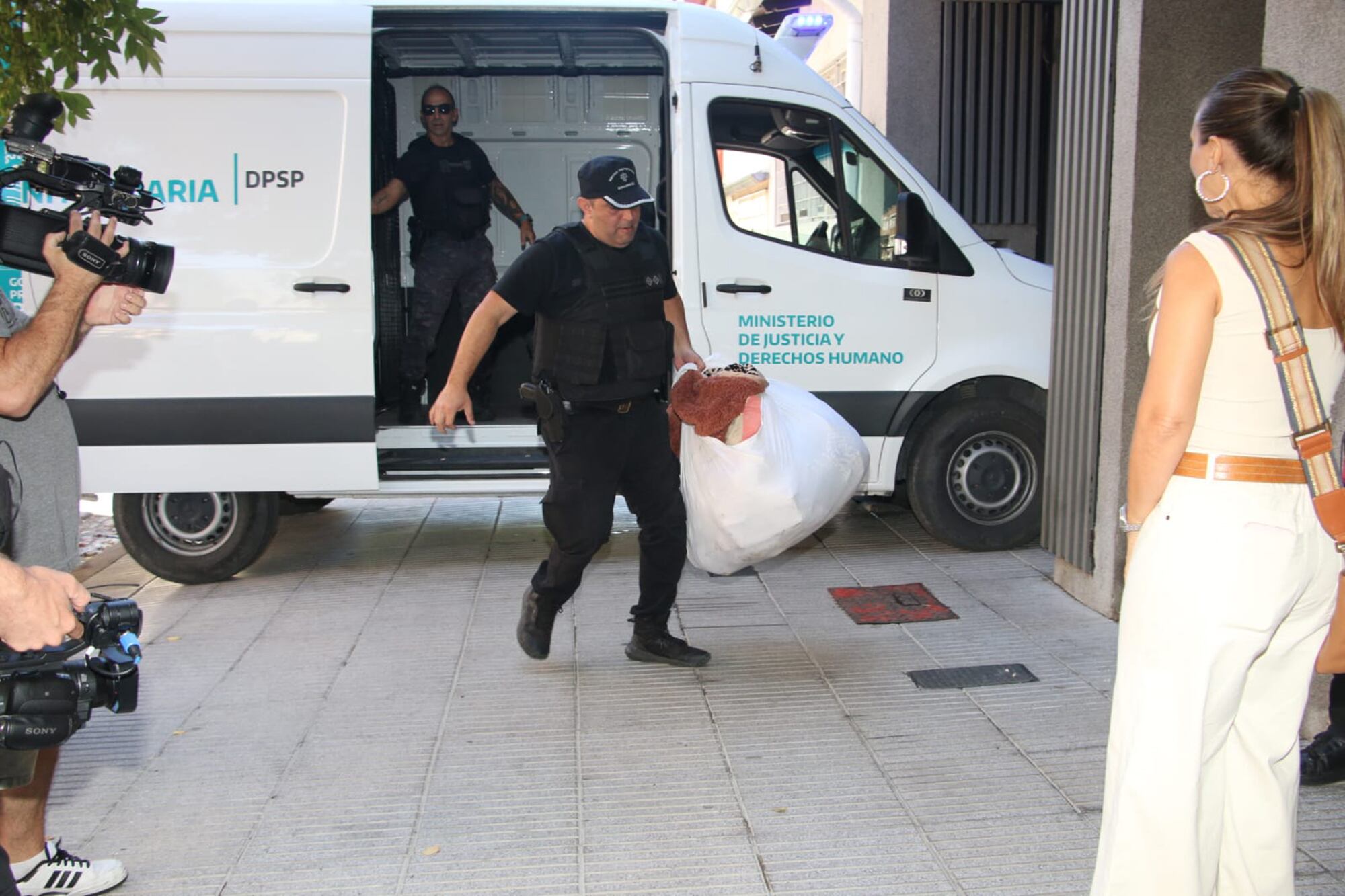 En la imagen, se ve a la policía bajando todas sus pertenencias en bolsas blancas