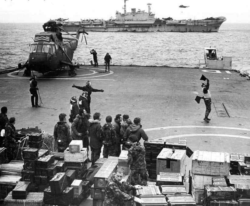 Sea King con las aspas plegadas a bordo de la cubierta de vuelo del HMS Intrepid. Atrás asoma el portaaviones ligero HMS Hermes.