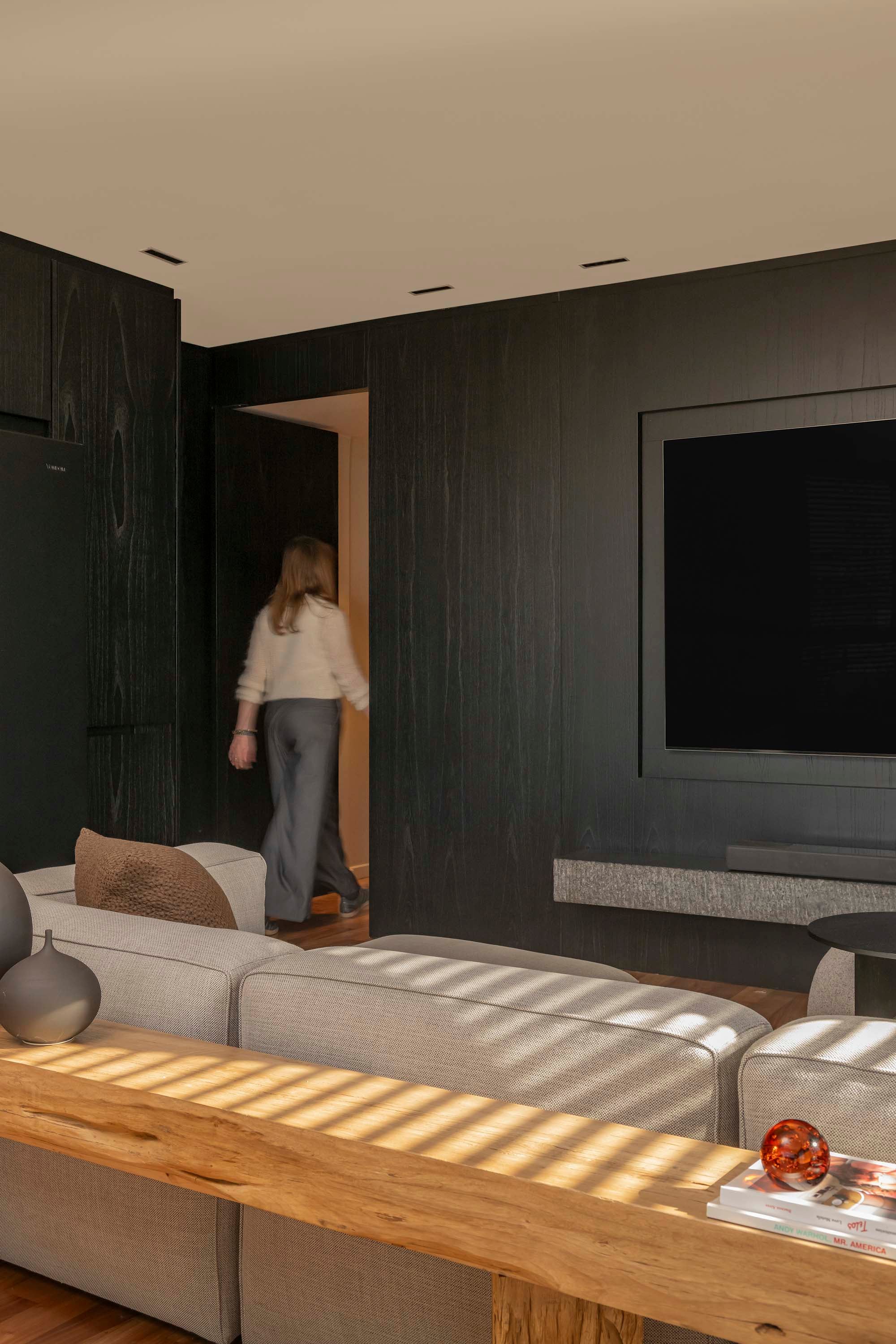 Una puerta oculta separa el área pública de la privada. Esta, al igual que el mueble TV, fue diseñada por el estudio y fabricada por Carpintería P&P. Marmolería (De Stefano).