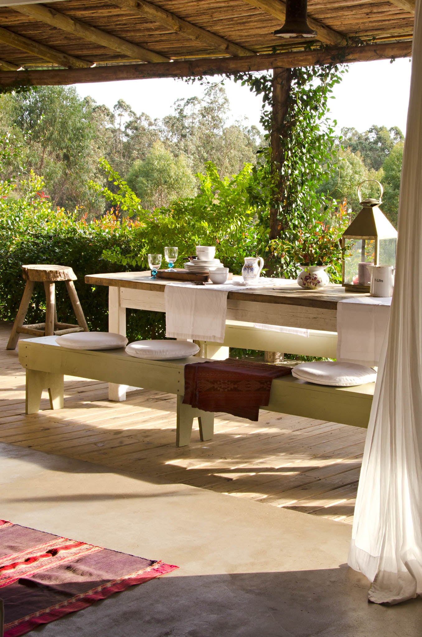 Muebles fuertes, textiles delicados y enredaderas que ya cubren los postes de eucalipto.