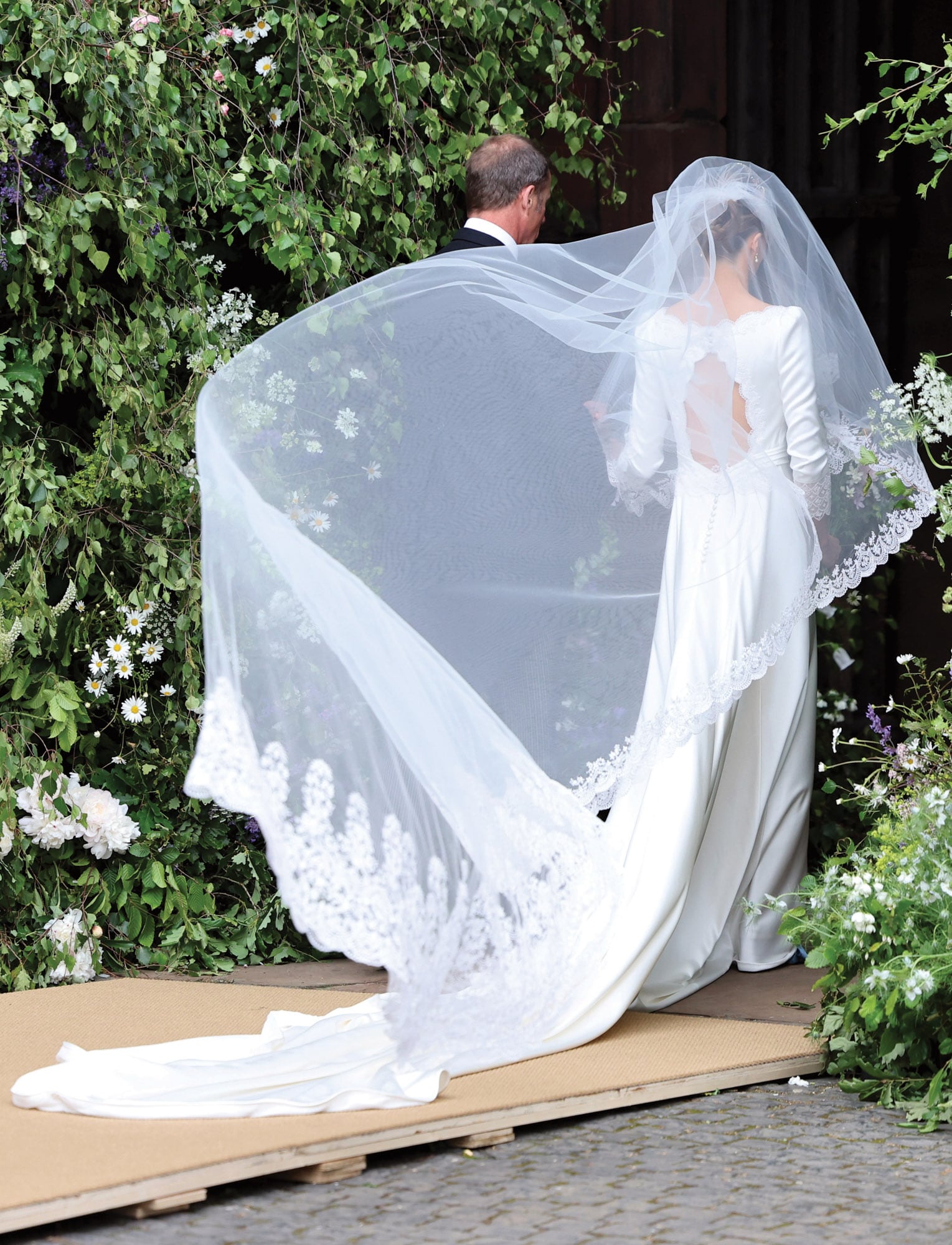 La novia ingresa del brazo de su padre, Ruper Henson. Una imagen, ayudada por el viento que hace volar el velo, que parece salida de una pelicula romántica. 
