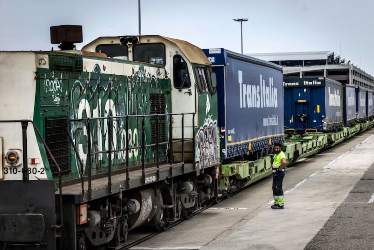Un tren procedente de Madrid llega al puerto de Valencia cargado con semirremolques de camiones. Los semirremolques procedentes de Italia bajan del buque, los colocan en fila y, gracias a los potentes brazos mecánicos de la máquina, se montan en un convoy con vagones especiales que los llevará hasta Madrid