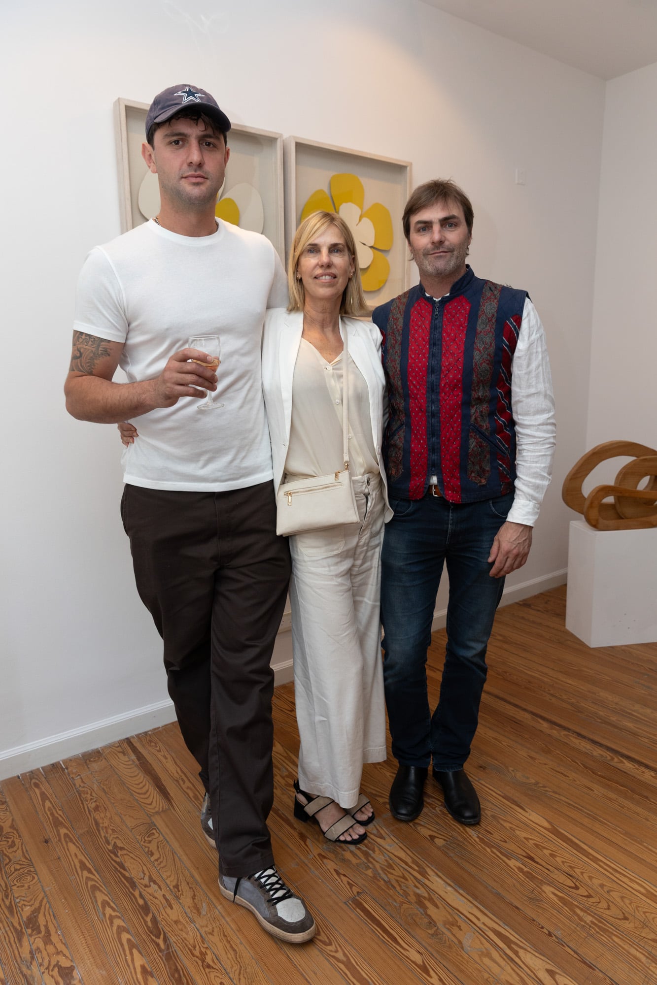 Jerónimo Pando con Alejandra Hoeffner y Eduardo Blaquier, primos de su mamá, Ginette Reynal. Detrás de ellos, tres obras de Alejandra: las flores y una escultura de madera