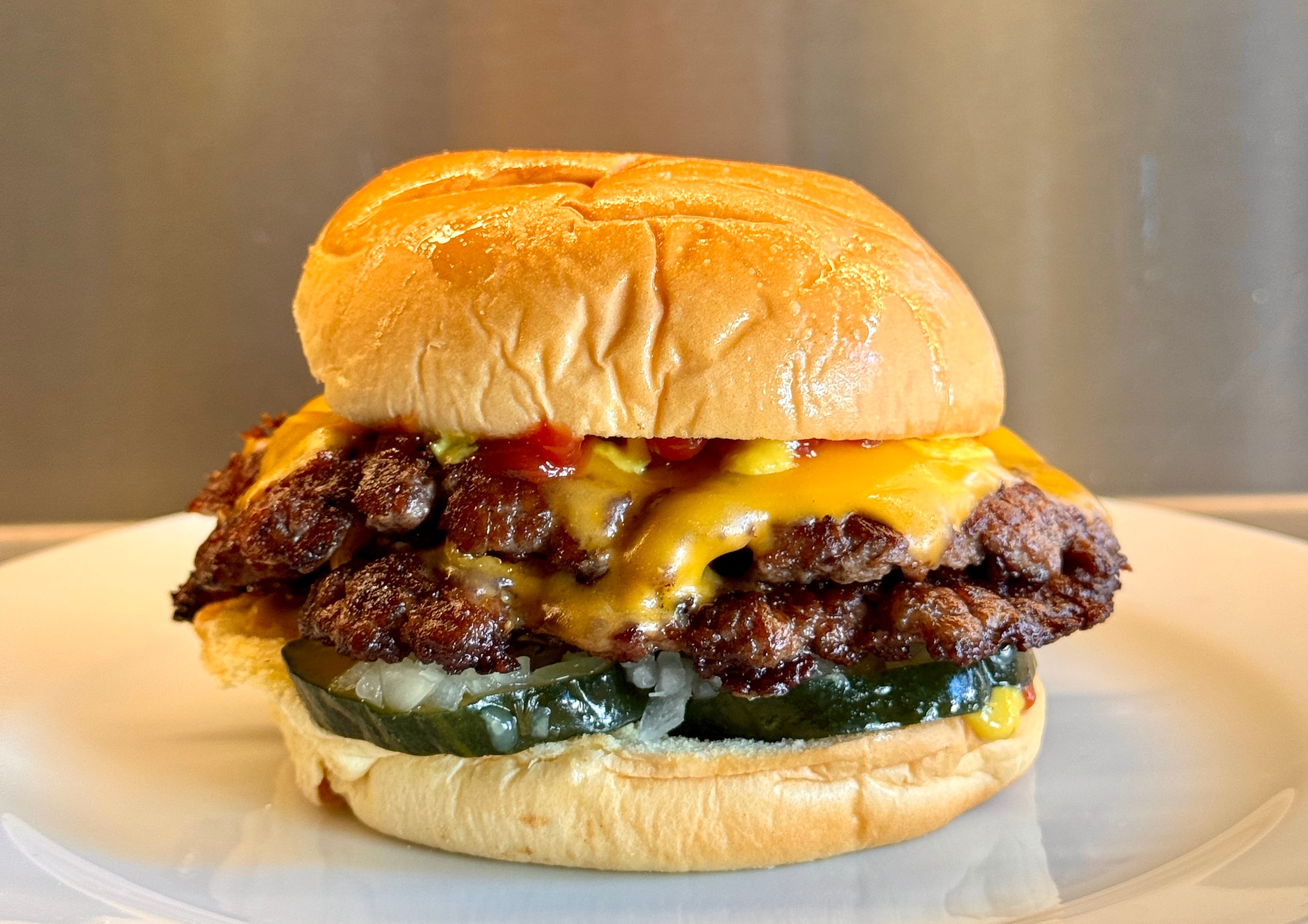 La Cheeseburger de Grasa con medallón smash simple o doble, cheddar, pickles de pepino, mostaza, ketchup y cebolla