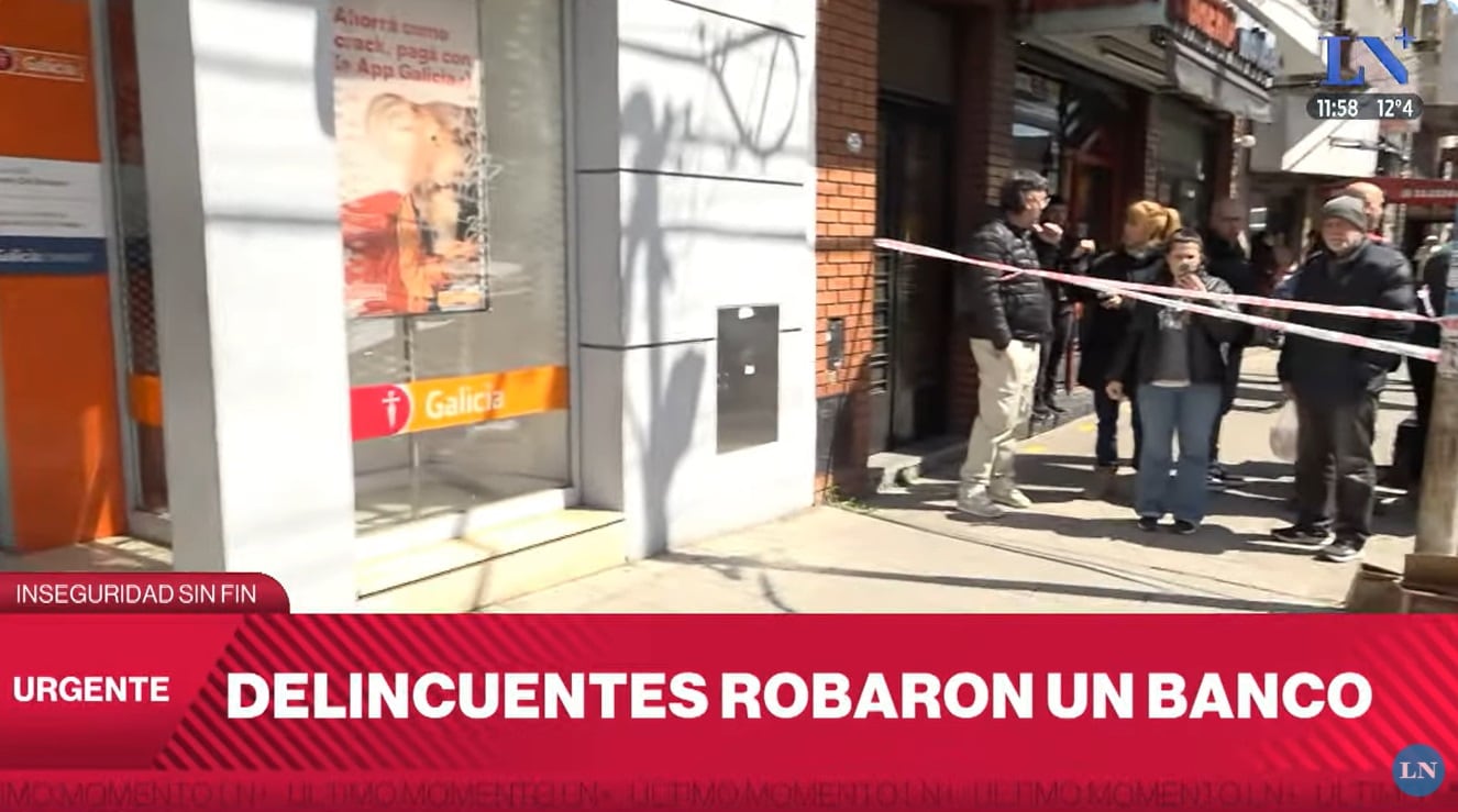 Vecinos observan el trabajo de la policía tras el asalto al Banco Galicia de Lomas del Mirador