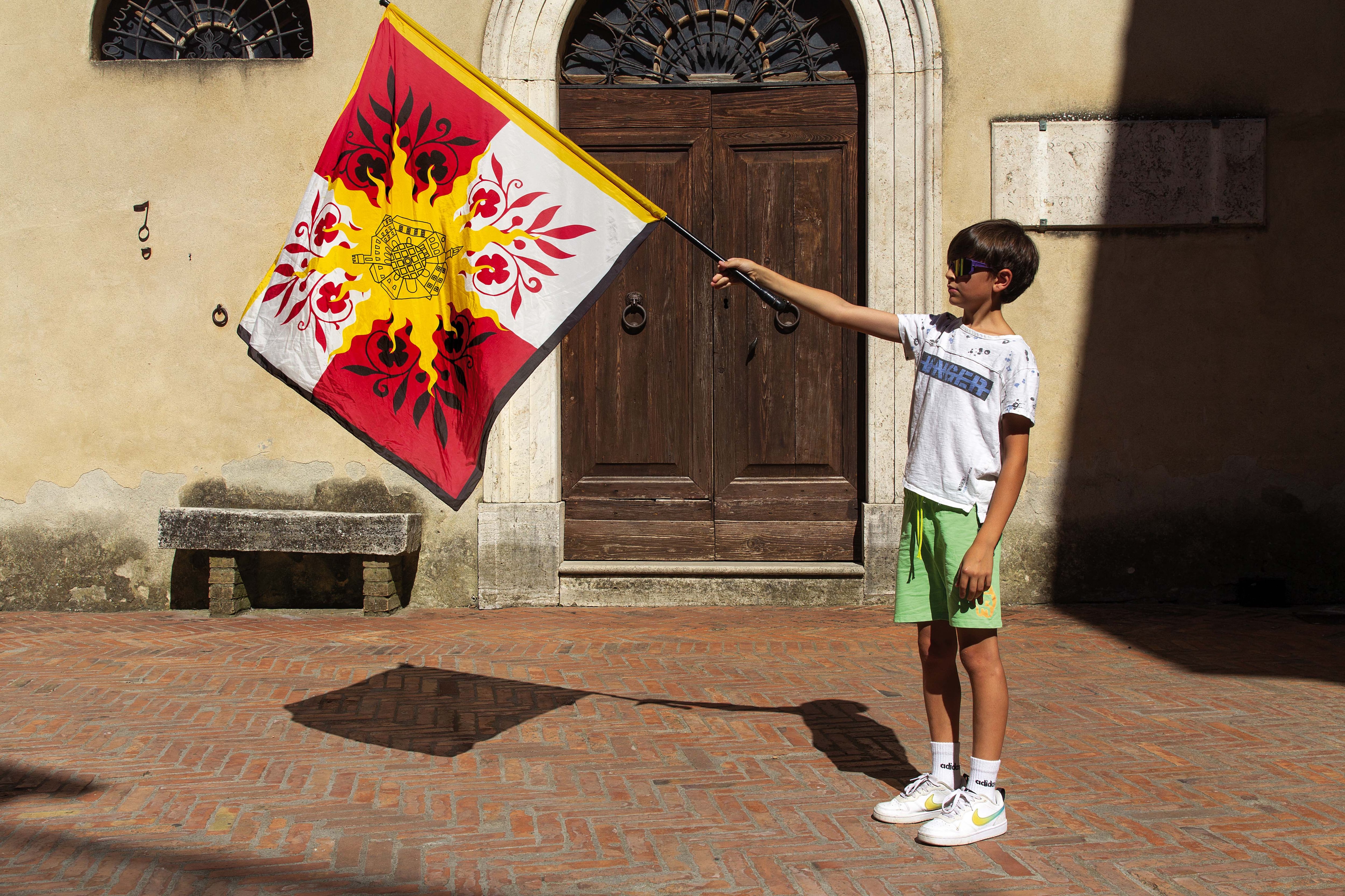 Leonardo juega con la bandera de Pienza en un callejón del pueblo.