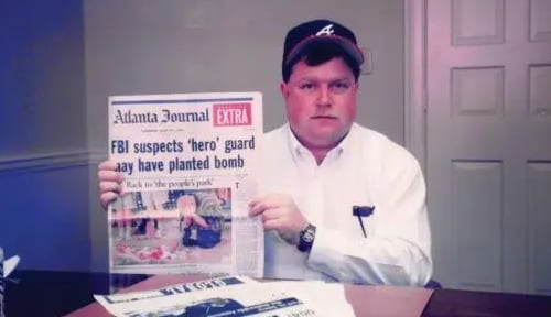 Richard Jewell sosteniendo una edición extra de The Atlanta Journal con el titular que lo señalaba como sospechoso: “FBI suspects ‘hero’ guard may have planted bomb” (“El FBI sospecha que el guardia ‘héroe’ pudo haber colocado la bomba”). Ese fue el titular que marcó el giro público del caso, apenas tres días después del atentado
