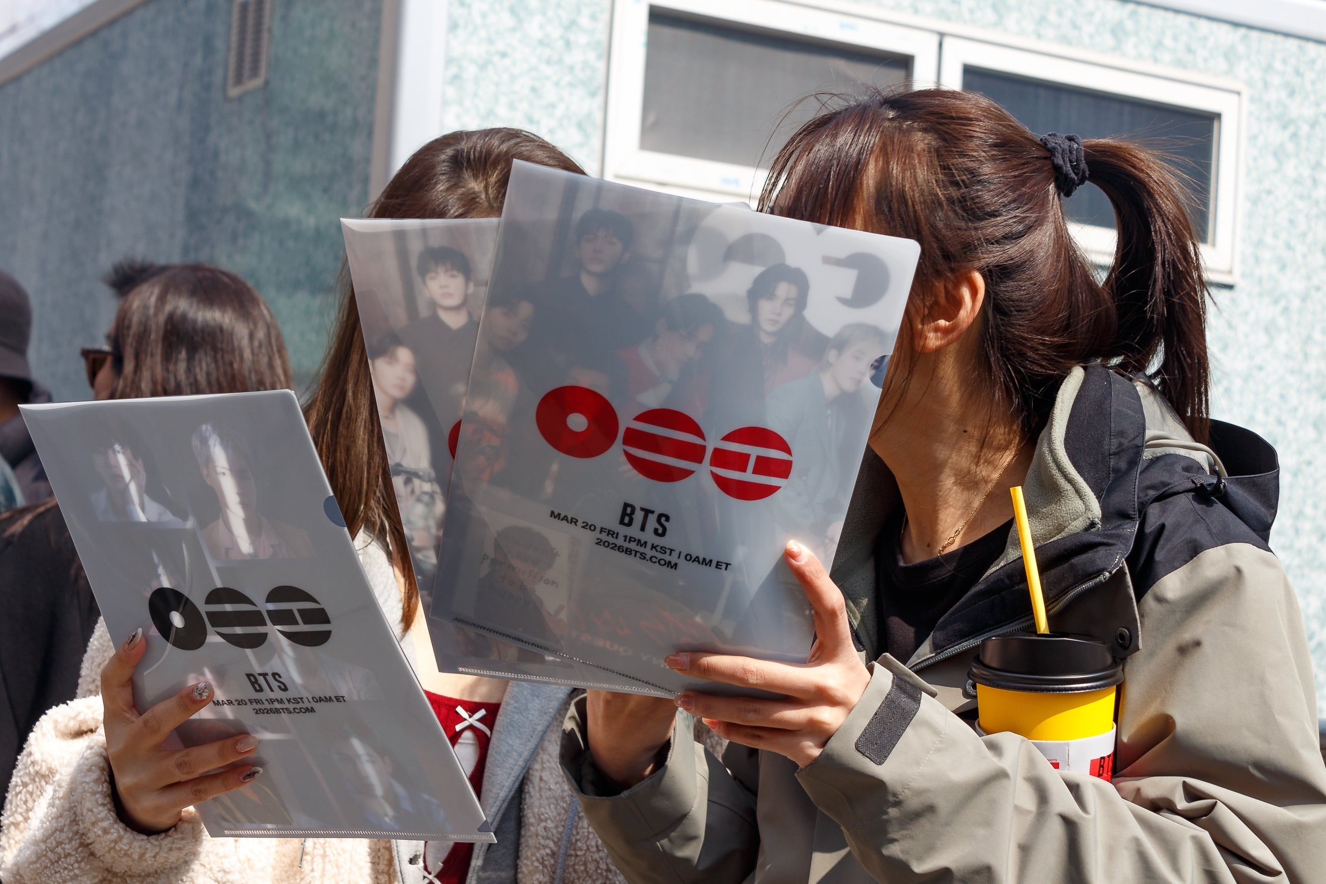En marzo de 2026, un grupo de fanáticos de BTS en la Plaza Gwanghwamun en Seúl, Corea del Sur, con volantes promocionales para el concierto de regreso de la banda