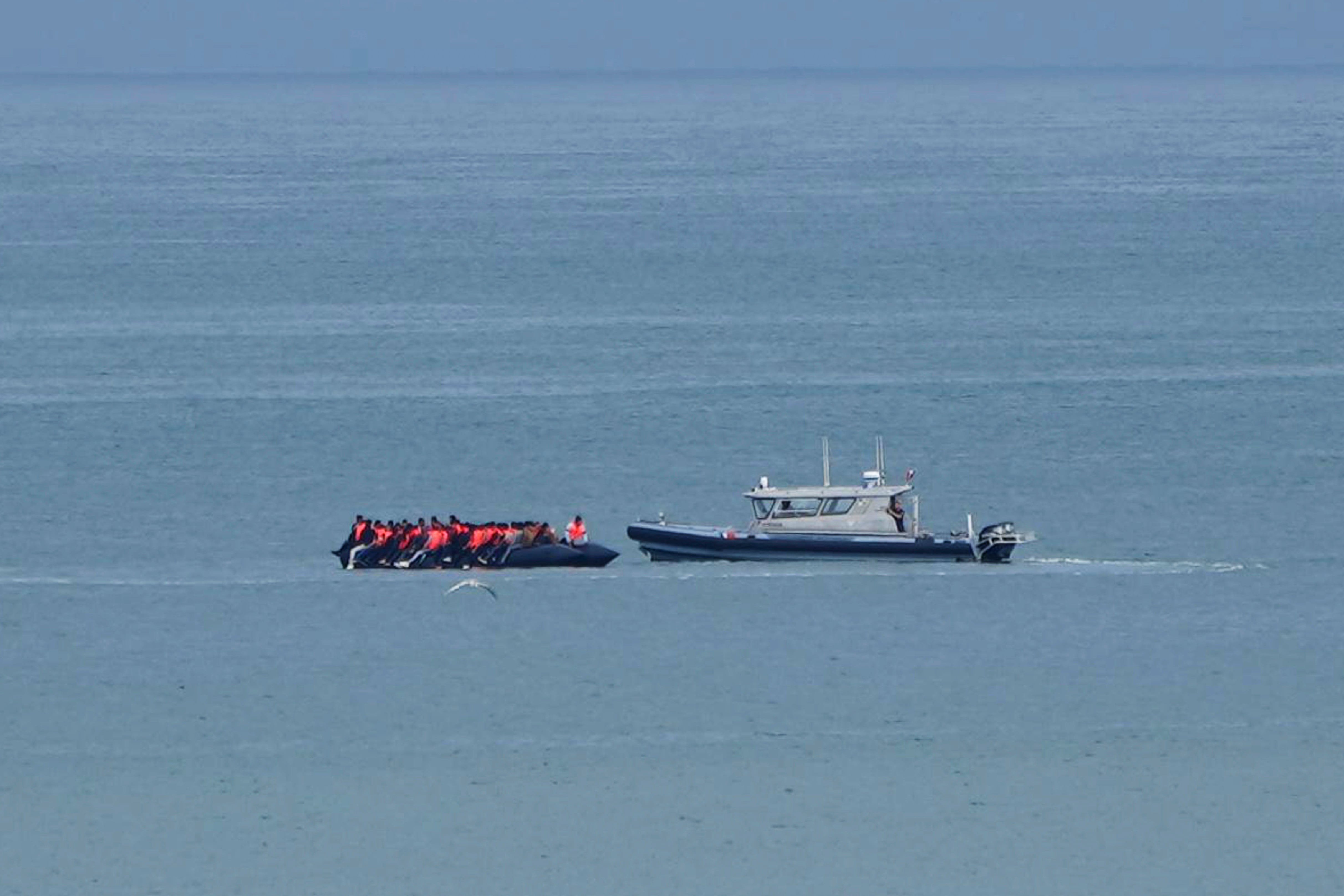 Un barco que se cree lleva migrantes es escoltado por un barco de la Gendarmería Nacional Francesa en el Canal de la Mancha junto a la playa de Wimereux, Francia