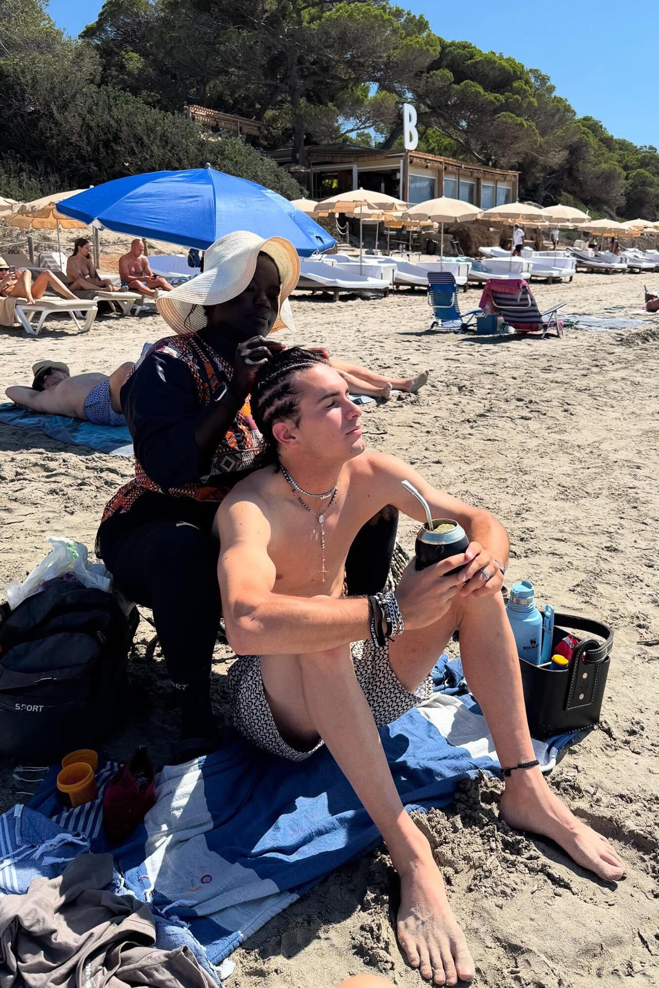 Mientras le trenzan el pelo, aprovecha para tomar unos mates.