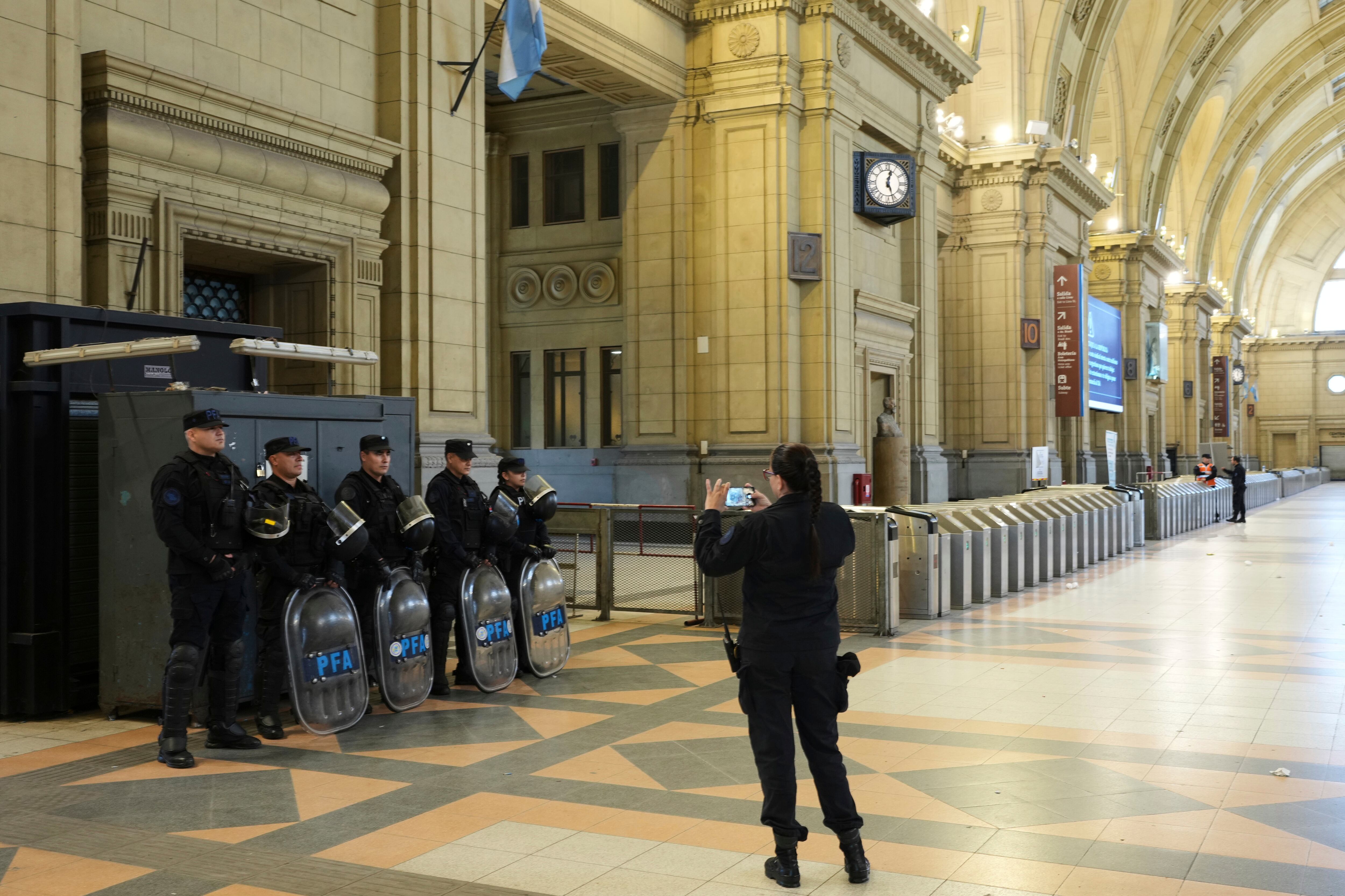 Una agente de policía toma una fotografía de sus colegas en la estación de tren de Constitución que está vacía