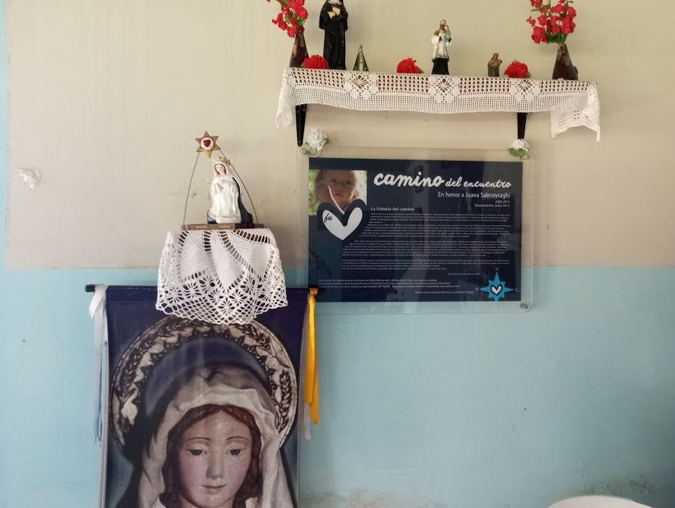 Pequeño altar en la posada El Fortín, en el Dique Campo Alegre. El cartel cuenta la historia del Camino a Salta. Hay detalles de la historia de Silvina y Diego, la pareja que tuvo la idea de abrir el camino tras la muerte de su hija Juana.