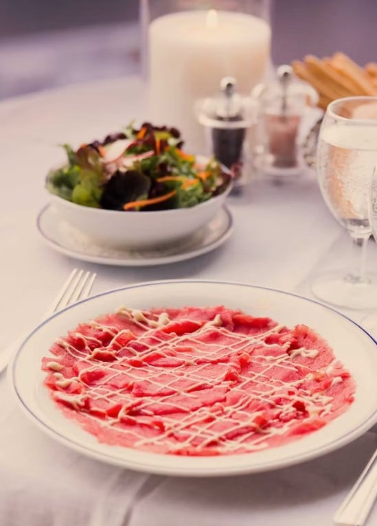 El carpaccio es un plato compuesto por finas láminas de carne cruda, aderezadas con aceite, limón o una salsa ligera