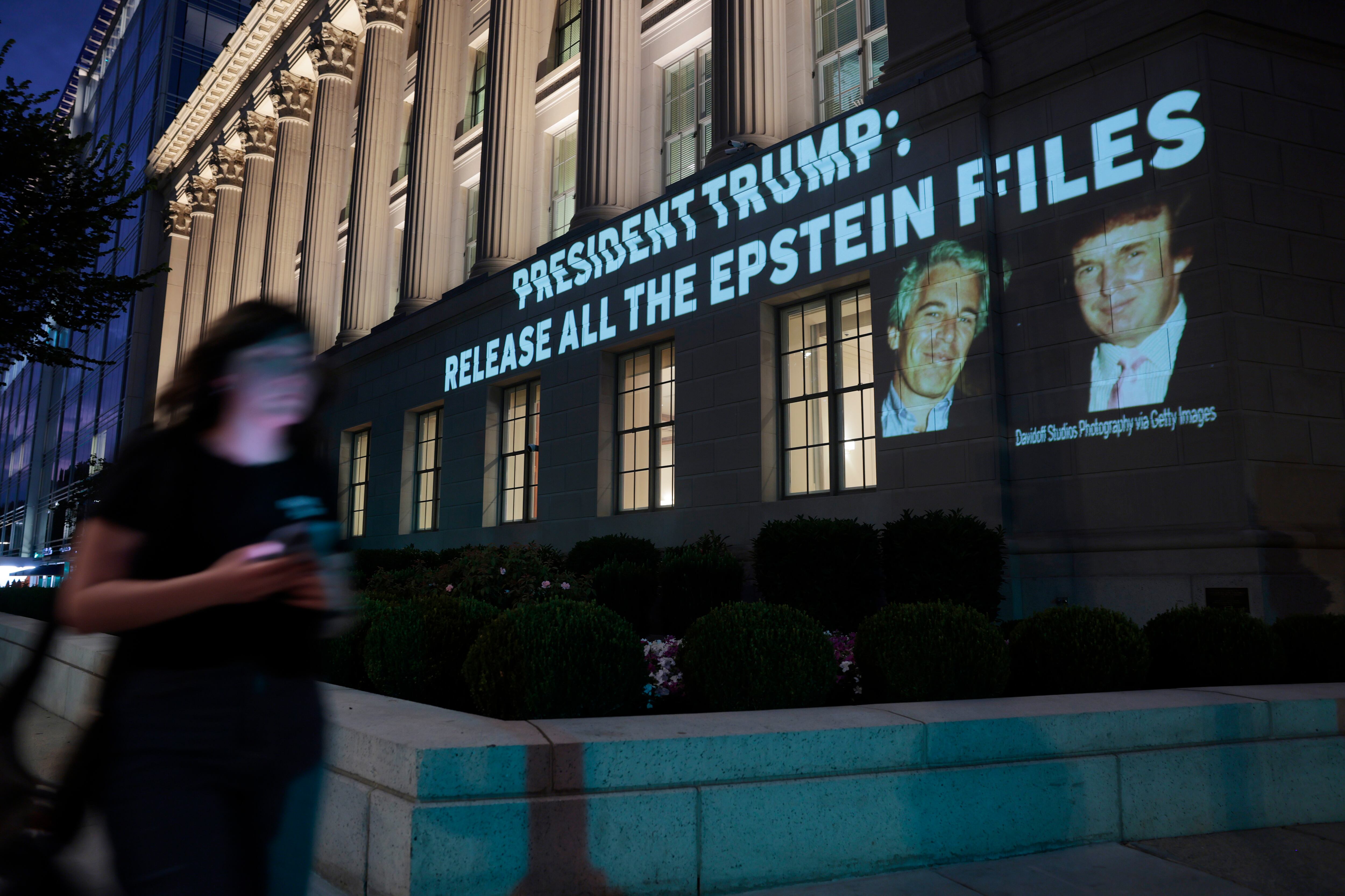 Una persona pasa junto a una imagen del presidente estadounidense Donald Trump y Jeffrey Epstein, junto con el mensaje