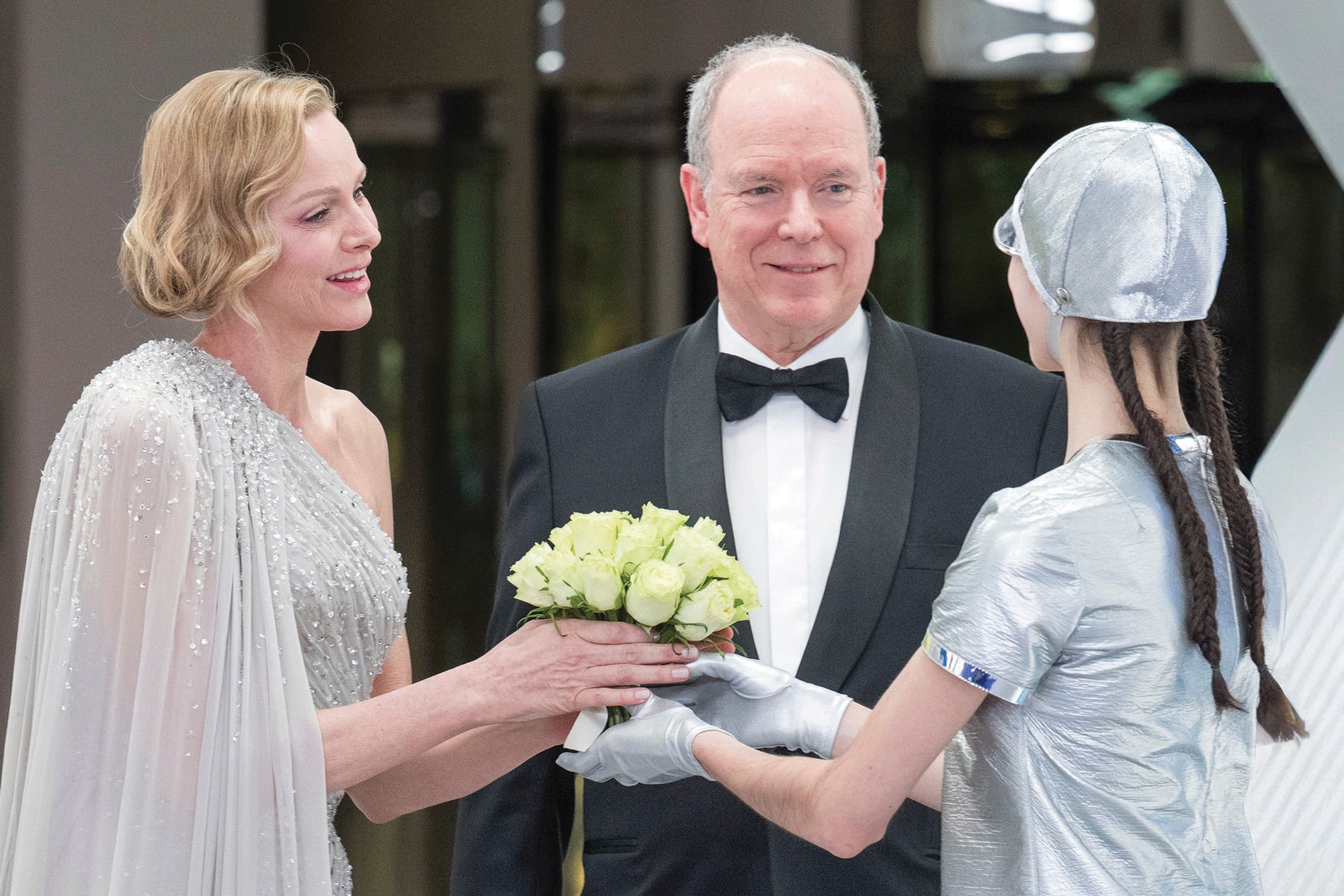 La princesa Charlene –en la foto junto a su marido, el príncipe Alberto II– optó por uno de sus diseños favoritos, el vestido capa con un hombro al descubierto. Firmado por Elie Saab, cumplió con la temática de la gala: plateado y salpicado de brillantes cristales
