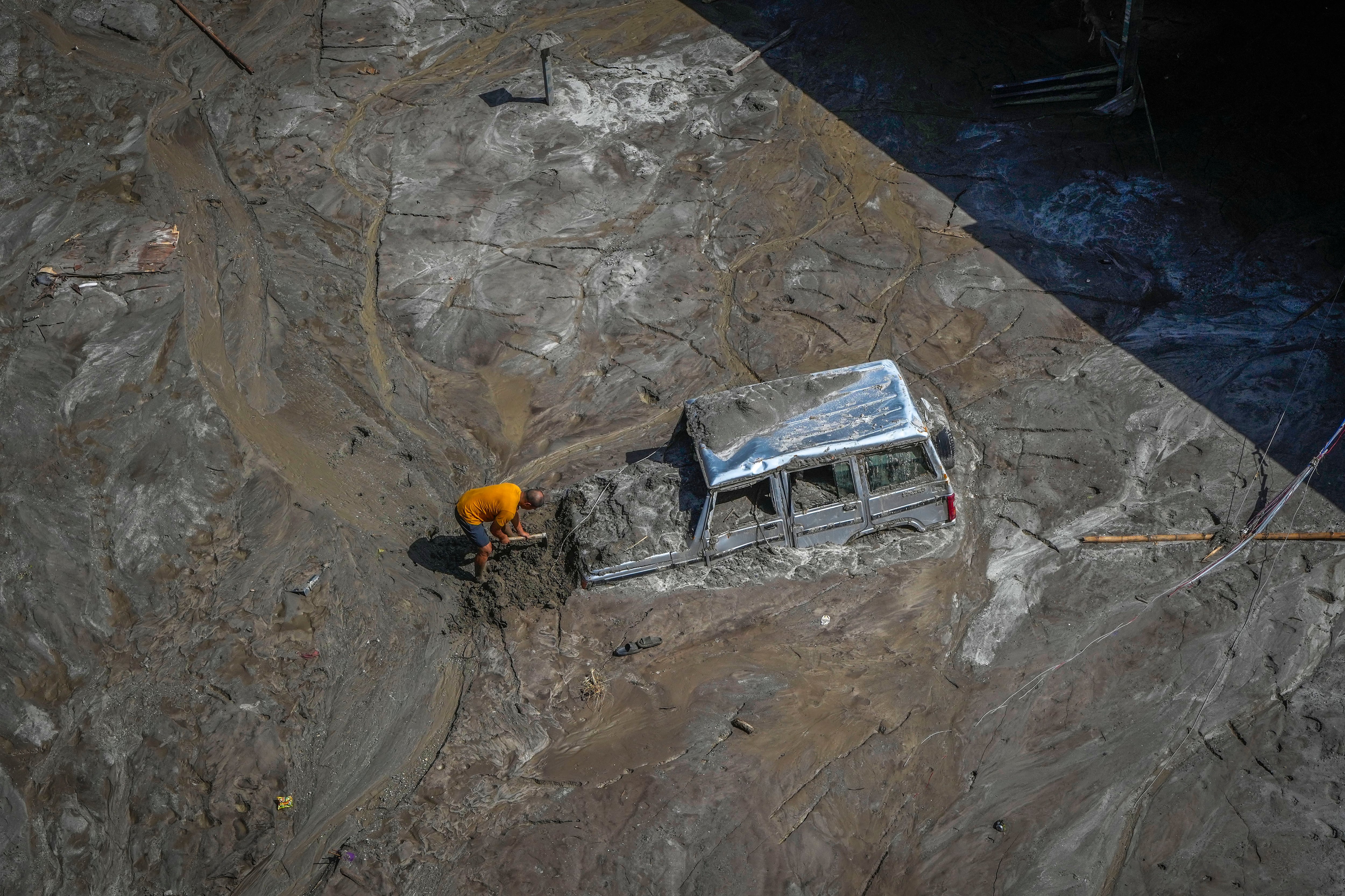 ARCHIVO - Un hombre trata de recuperar un vehículo cubierto de lodo en una zona afectada por una inundación a lo largo del río Teesta, en el noreste de India, el 8 de octubre de 2023. (AP Foto/Anupam Nath, archivo)