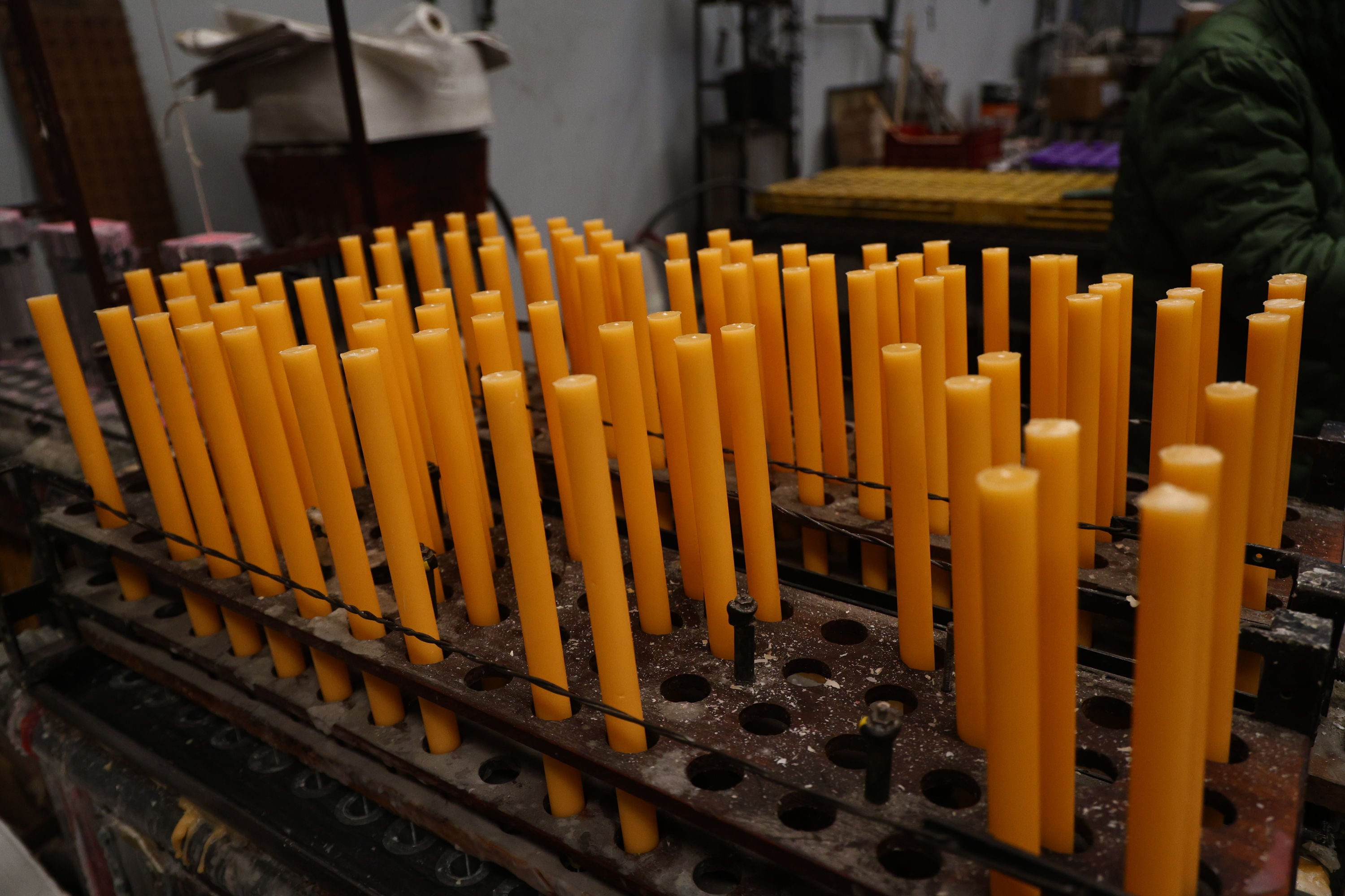 Las velas de cera de abeja avanzan alineadas por una de las máquinas de Lumen Christi, donde parte de la producción se realiza de manera mecanizada
