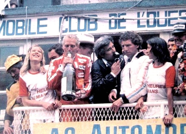 El podio de Le Mans: Paul Newman de festejo, mientras Rolf Stommelen habla con los medios