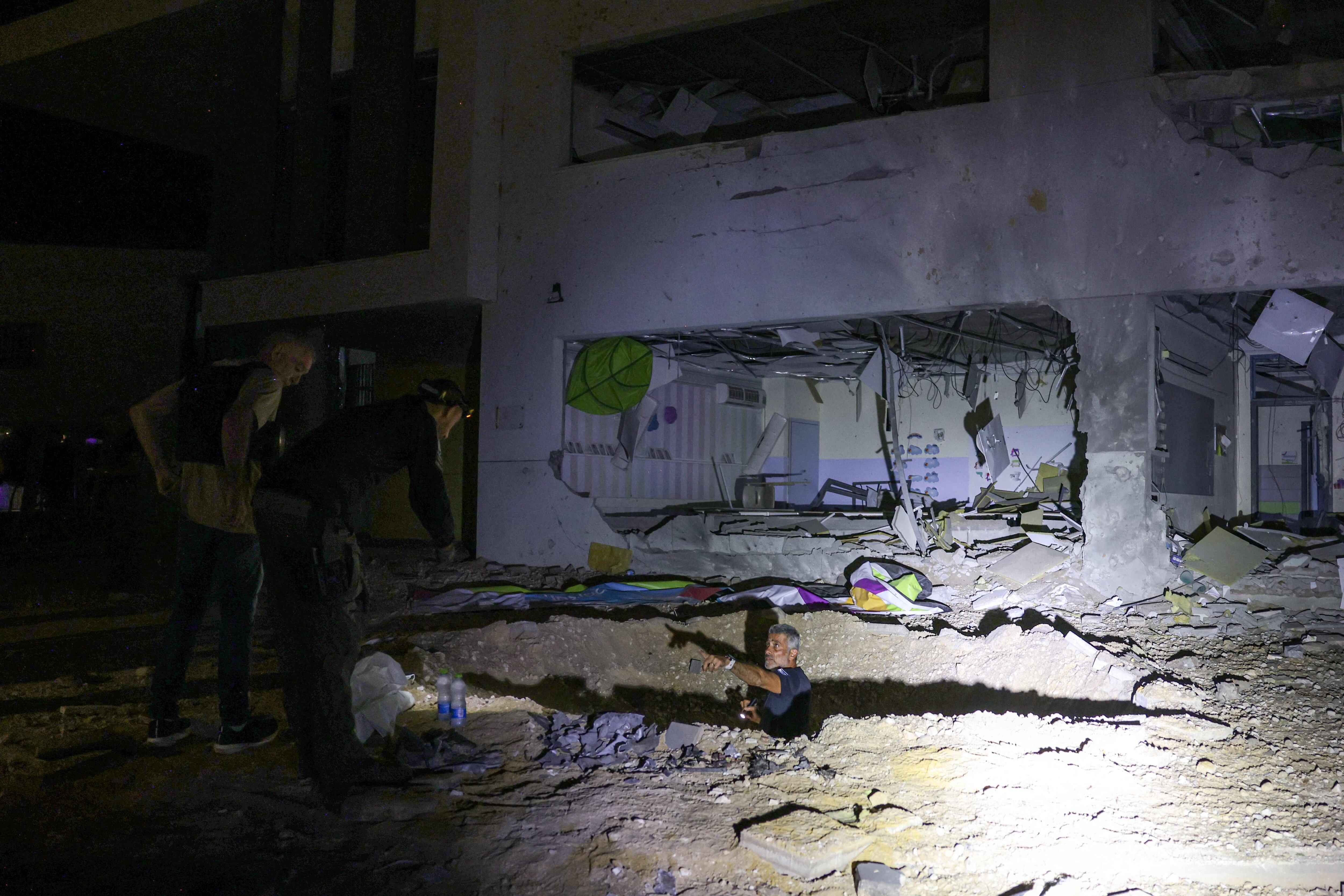 Miembros del Home Front Command de Israel inspeccionan un cráter en Gedera, tras la caída de un misil iraní. (Menahem KAHANA / AFP)