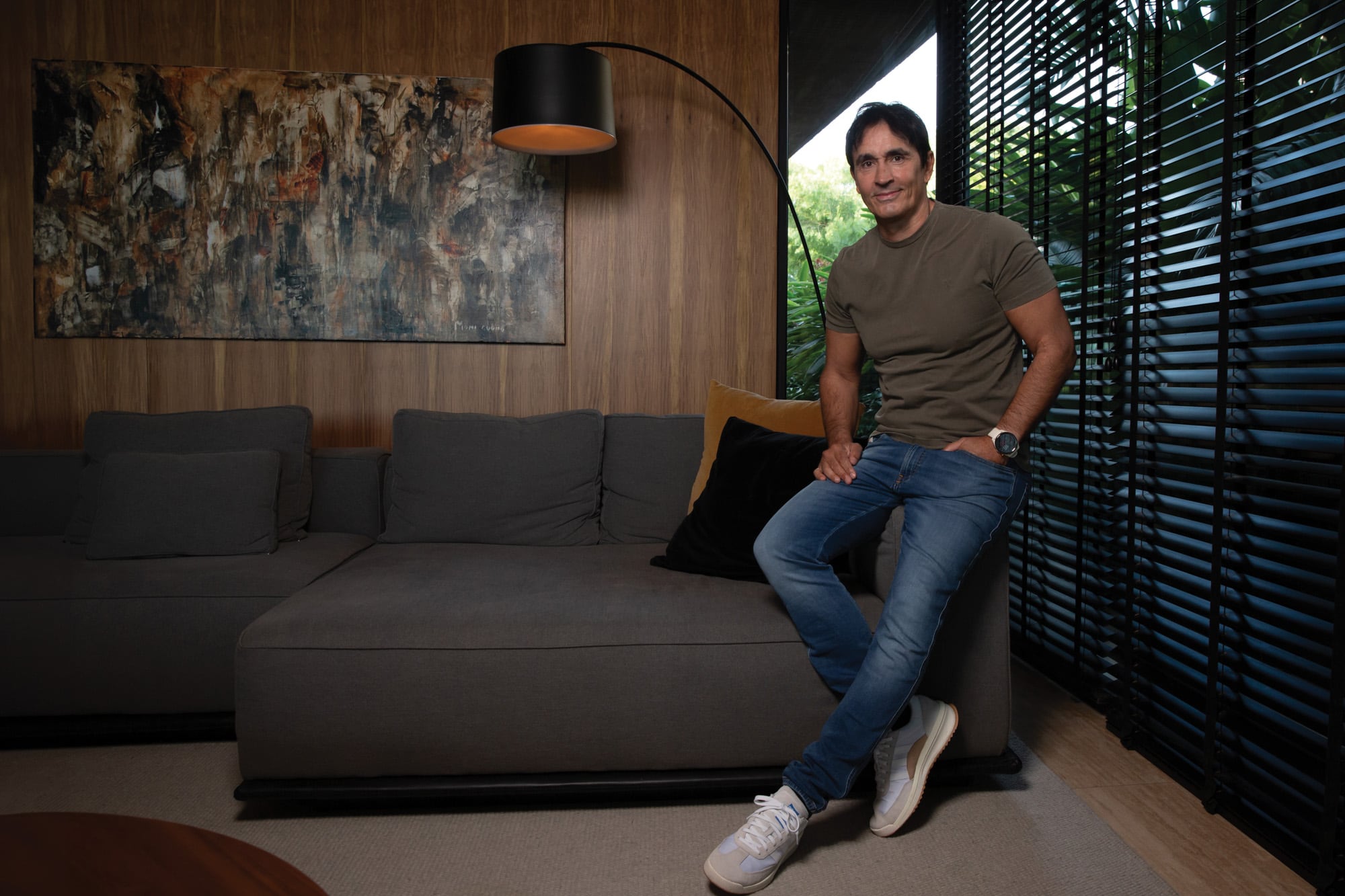 Sebastián Estevanez
posa en un rincón de
su living, decorado en
colores oscuros y con
detalles de madera.
Detrás de él, un
cuadro pintado por su
madre, la artista Moni
Cuomo.