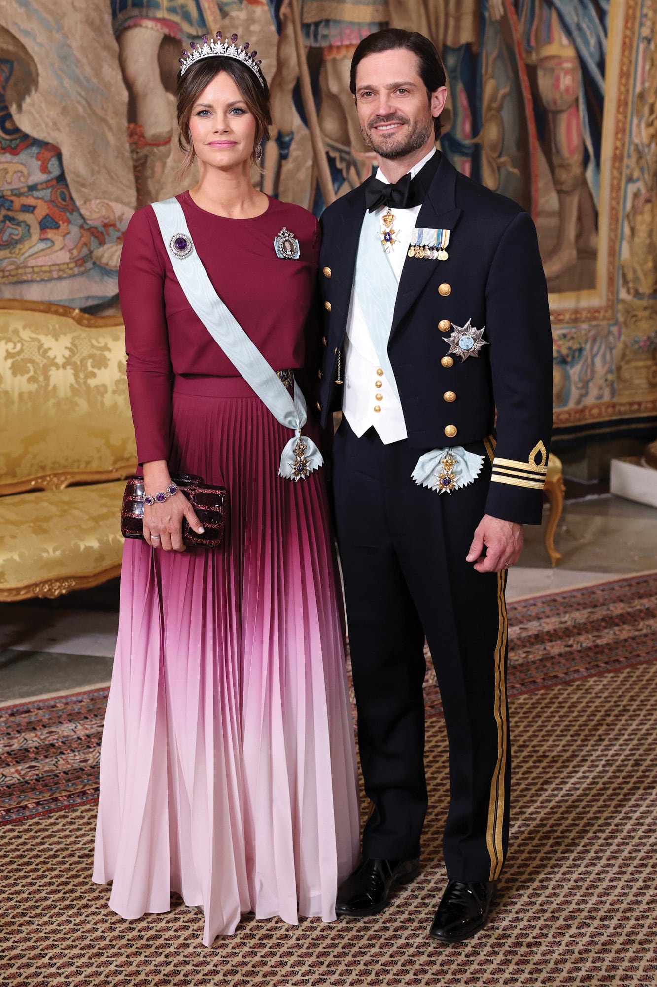 Espectacular con un vestido borravino en degradé, de manga larga, corte a la cintura y falda plisada, de la diseñadora Lilli Jahilo, la princesa Sofía fue de las más miradas de la noche. Complementó su estilismo con un clutch Gucci y Palmette, su tiara favorita, una joya de diamantes y amatistas que lució con broche, pendientes y pulsera a juego. A su lado, su marido, el príncipe Carlos Felipe
