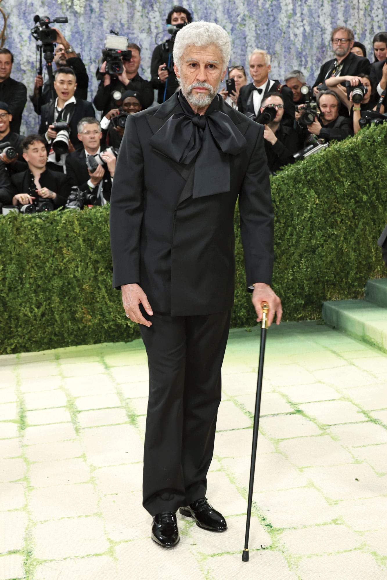 Las apariciones de Bad Bunny en la Met Gala son una declaración. Este año, quiso poner sobre el tapete la normalización de la juventud: apareció con el pelo blanco y arrugas en la cara, cuello y manos, un efecto logrado por el maquillador Mike Marino. El smoking, que codiseñó junto con Zara, hacía referencia al traje de 1947 del diseñador Charles James. Como accesorios, un reloj y un bastón
