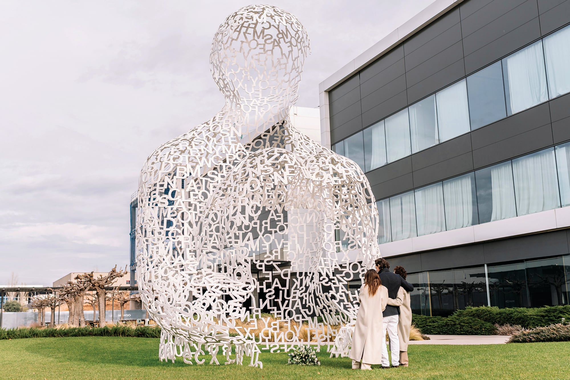 Los tres hijos del fundador de Mango abrazados en señal de unidad fraternal frente a la escultura del artista Jaume Plensa titulada House of Knowledge
