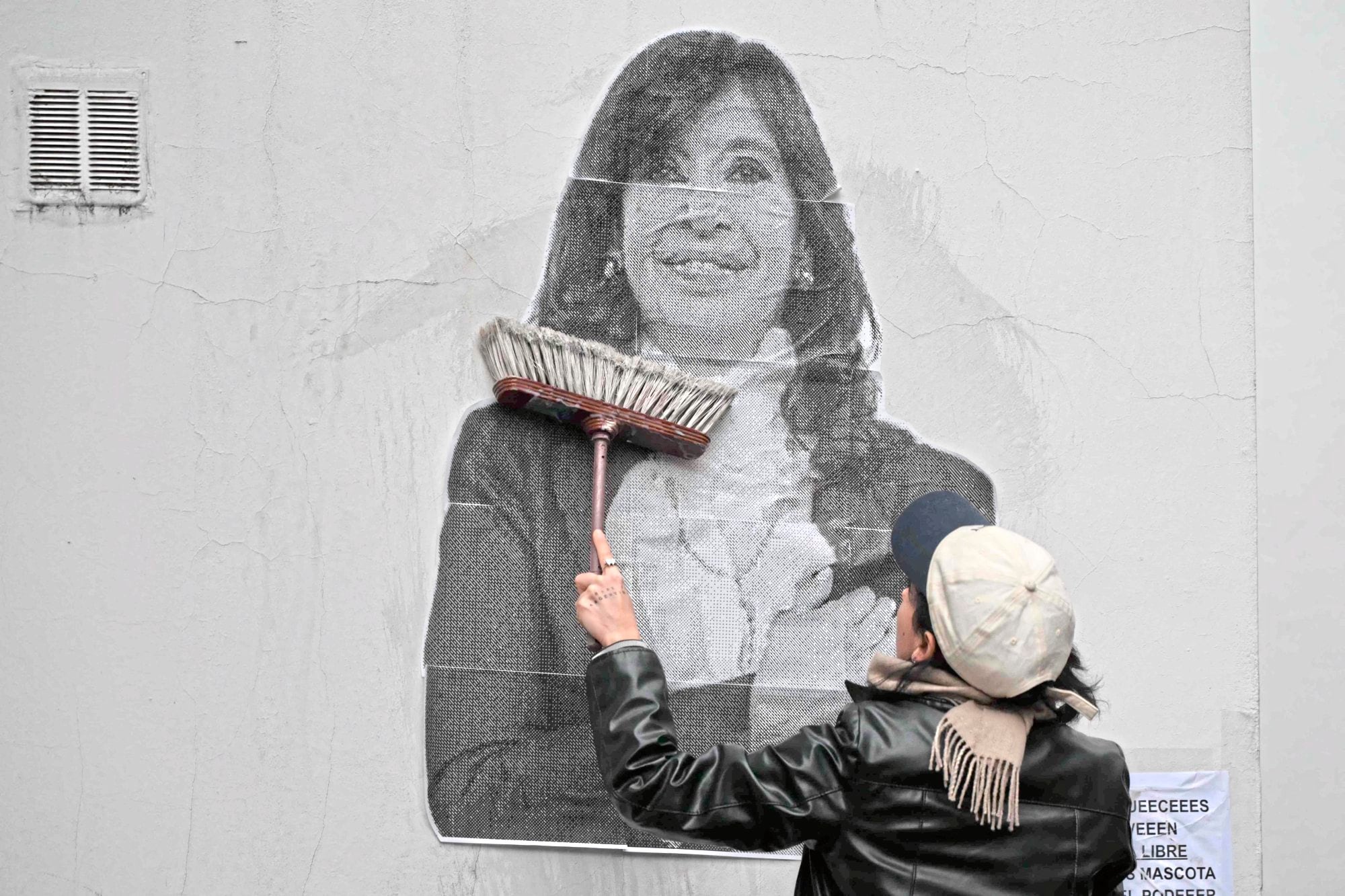 Una simpatizante de la expresidenta argentina Cristina Fernández de Kirchner pega un cartel frente a su residencia en Buenos Aires el 17 de junio de 2025, un día antes de su comparecencia ante las autoridades para cumplir su condena de seis años de prisión por corrupción.