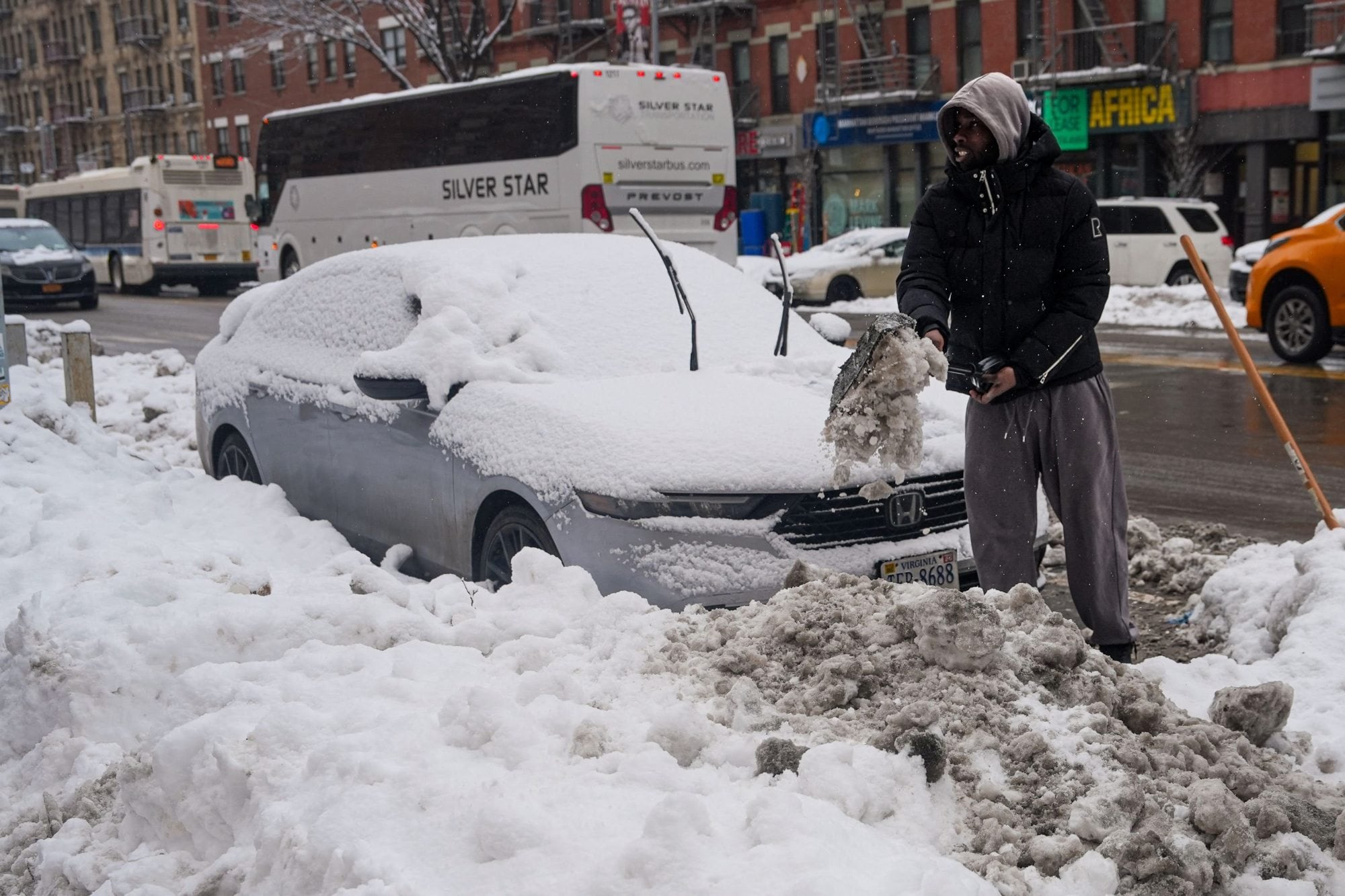 Un hombre remueve la nieve de un auto en el barrio de Harlem, en Nueva York (Photo by RYAN MURPHY / GETTY IMAGES NORTH AMERICA / Getty Images via AFP)